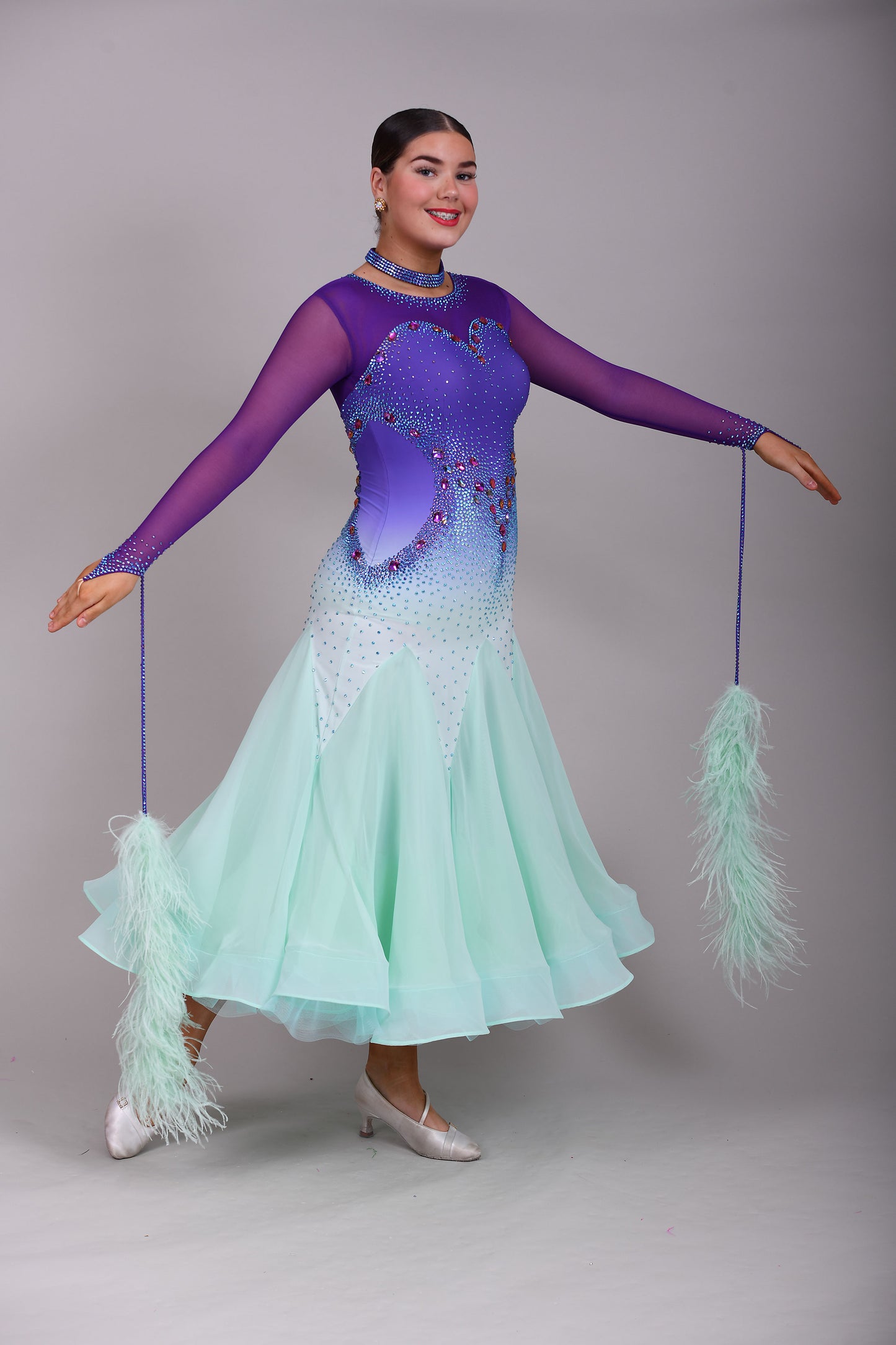 167 Ombré purple to mint green competition Ballroom dance dress. Stoned in mint green, mint green ab, purple & vitrail. Ostrich feather floats attached to stoned strips. High back to give the option of wearing own bra.