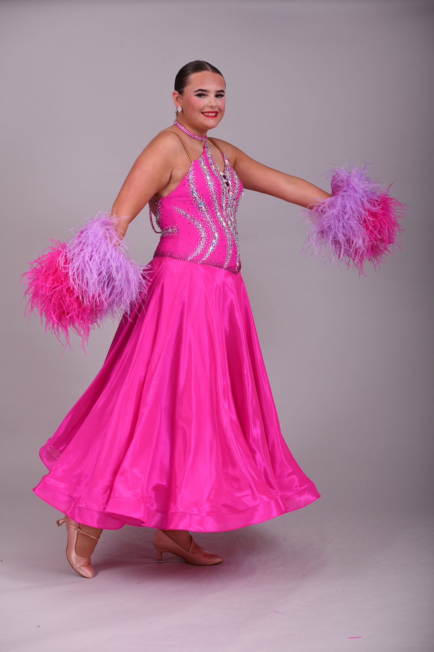 005 Cerise Pink Competition Ballroom Dance Dress. Heavily stoned in AB and Fuchsia & lilac. Comes with ostrich cuffs in Lilac & Cerise. Beautiful back detail.