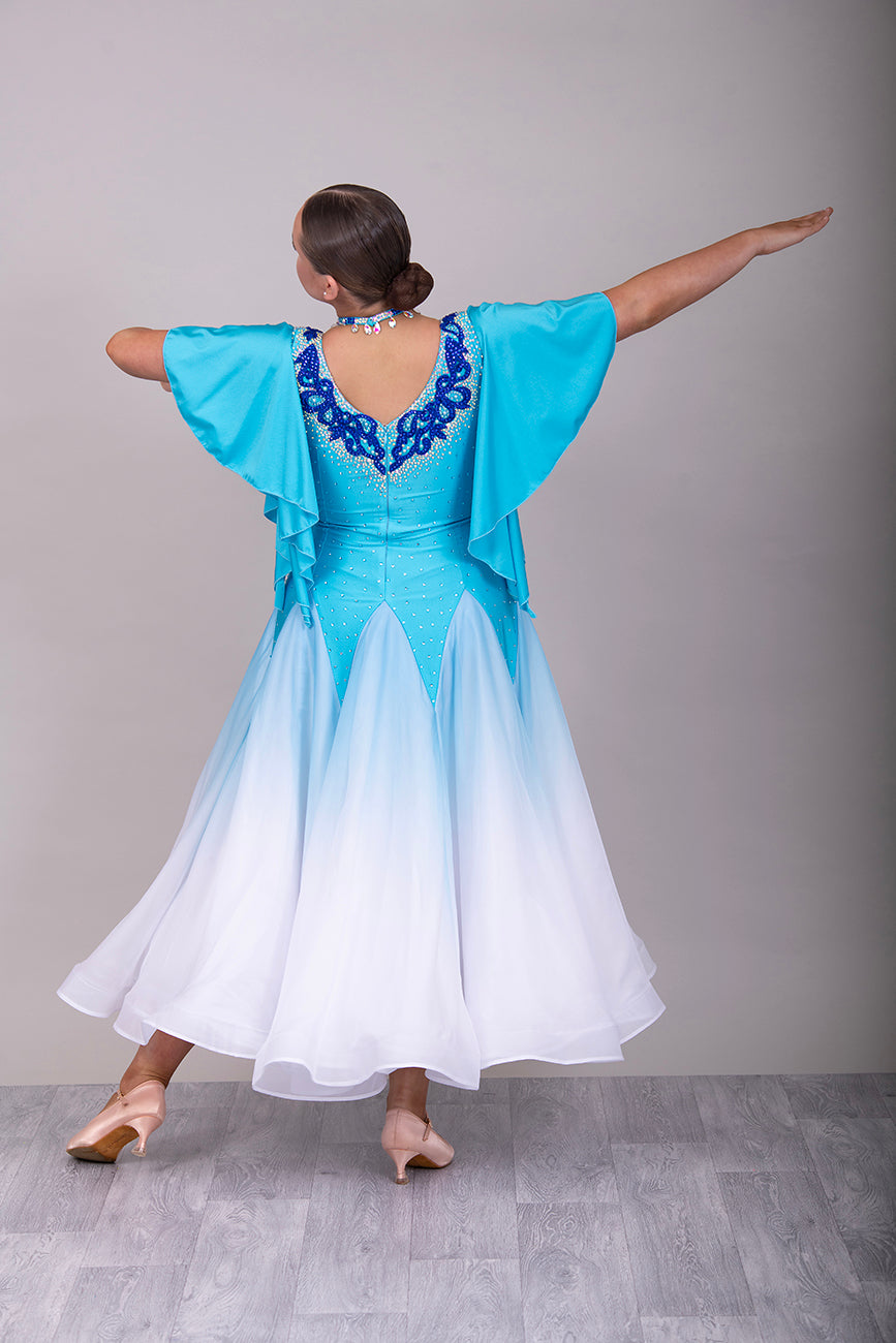 034 Turquoise & White ombré Ballroom Dress. Feature floaty sleeves & flesh panel detail to the chest. Decorated with royal blue motifs. Stoned in sapphire, light sapphire & AB