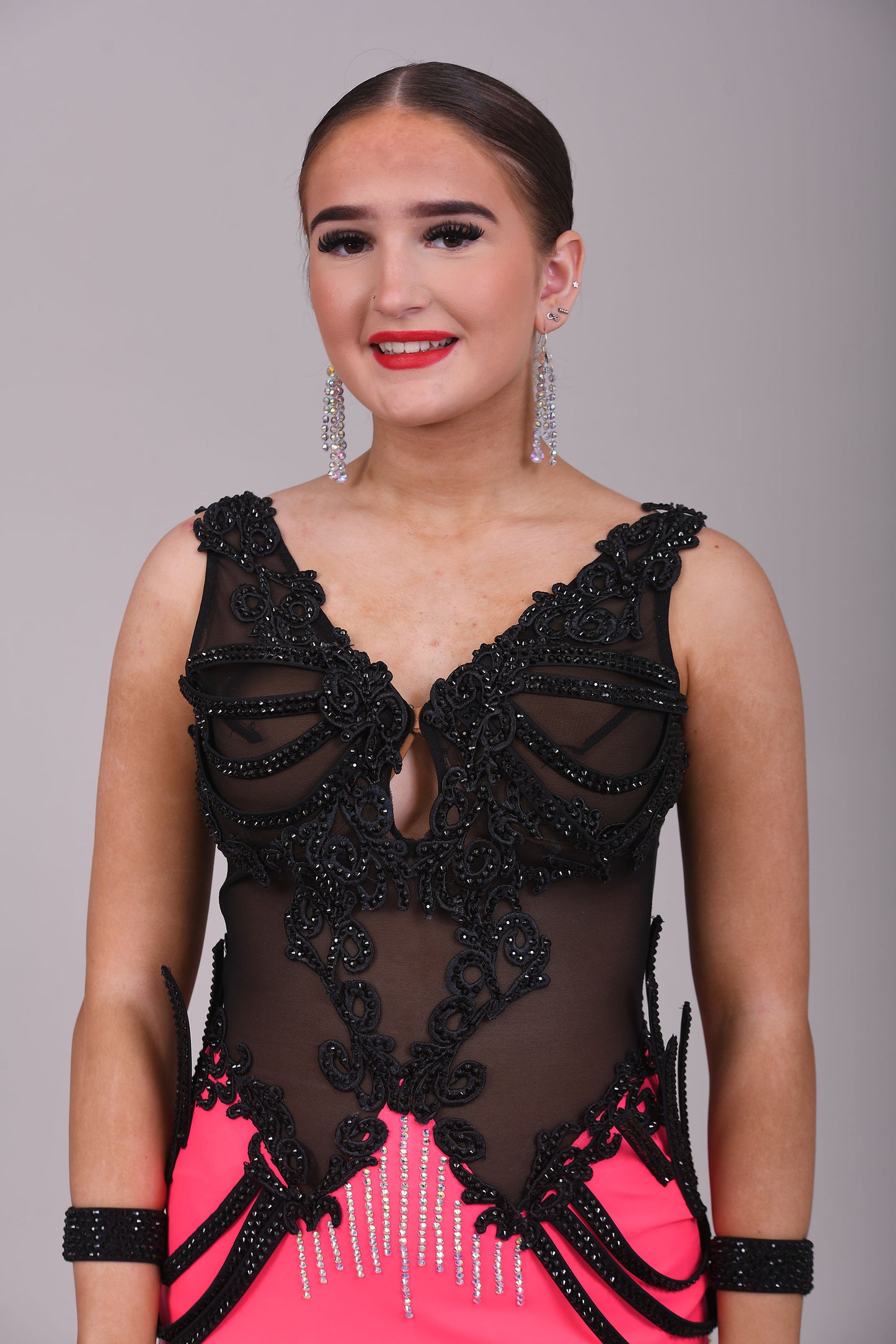 084 Black & Electric Pink Latin Dress. Black mesh bodice decorated with black appliqué & jet stones. Stoned material hip straps. Skirt decorated in AB
