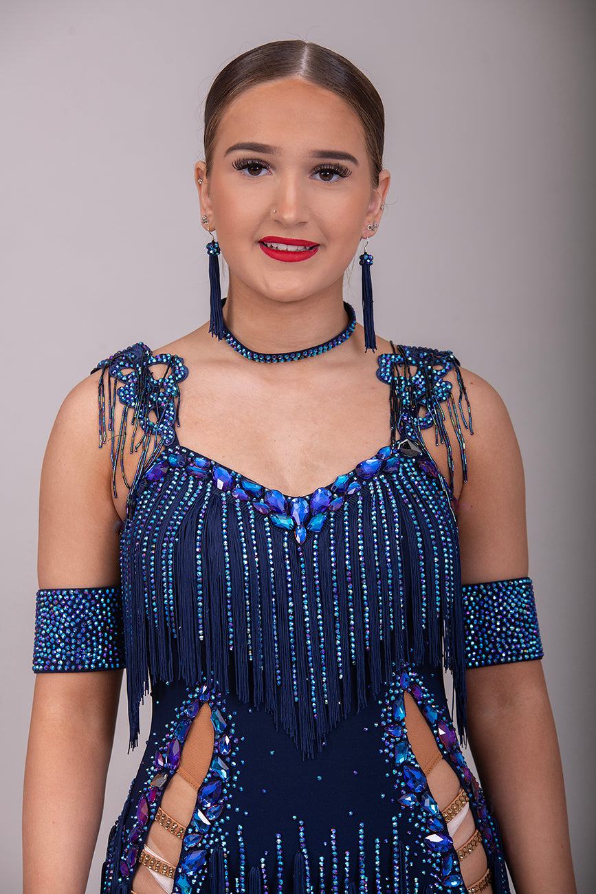 14L Navy Blue Competition Latin/Rhythm Dress. Stoned Fabric Tassels for the Skirt & Upper Chest. Heavily Stoned in Blue AB & Blue. Strappy detailing to the Hips & Drape to the back