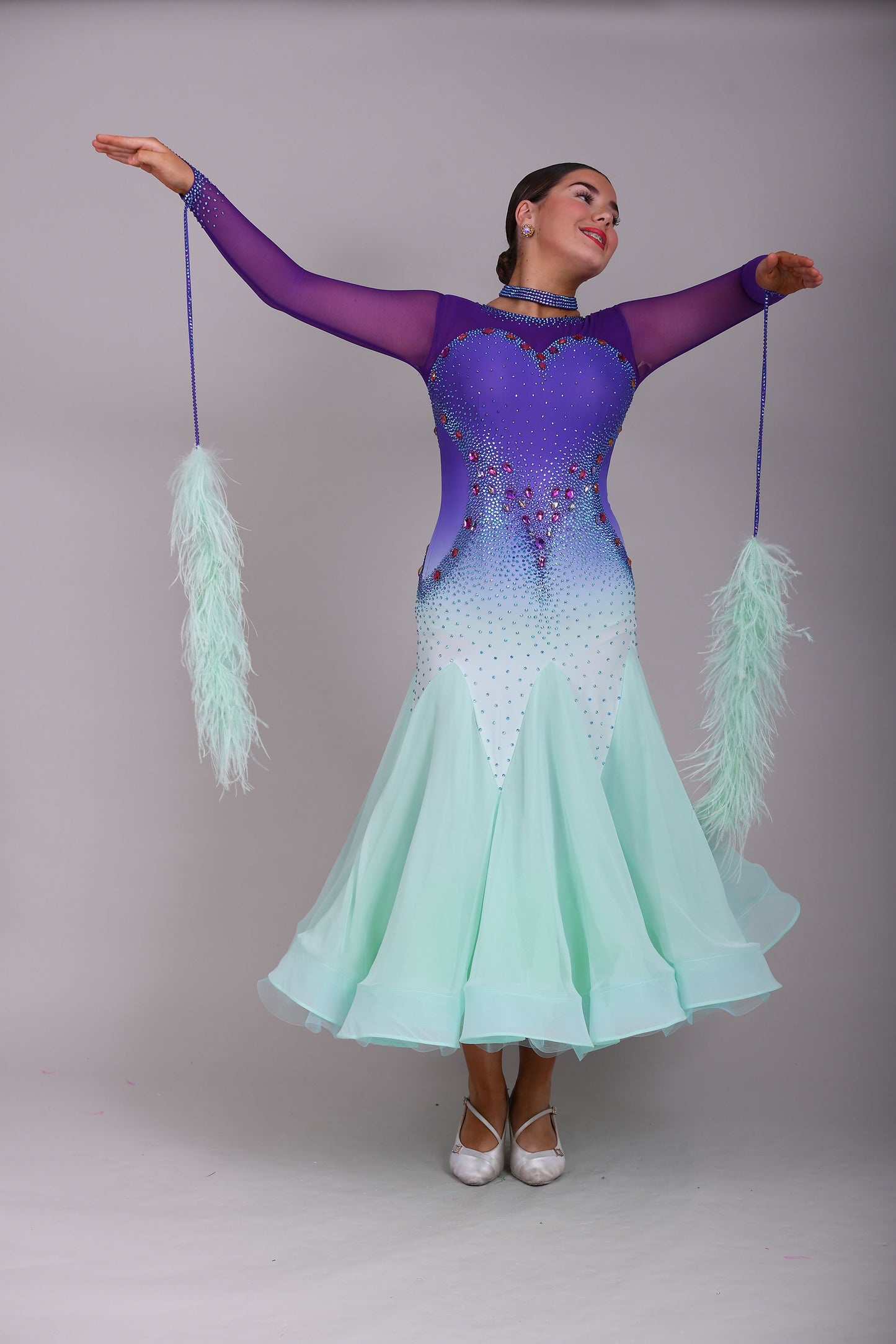 167 Ombré purple to mint green competition Ballroom dance dress. Stoned in mint green, mint green ab, purple & vitrail. Ostrich feather floats attached to stoned strips. High back to give the option of wearing own bra.