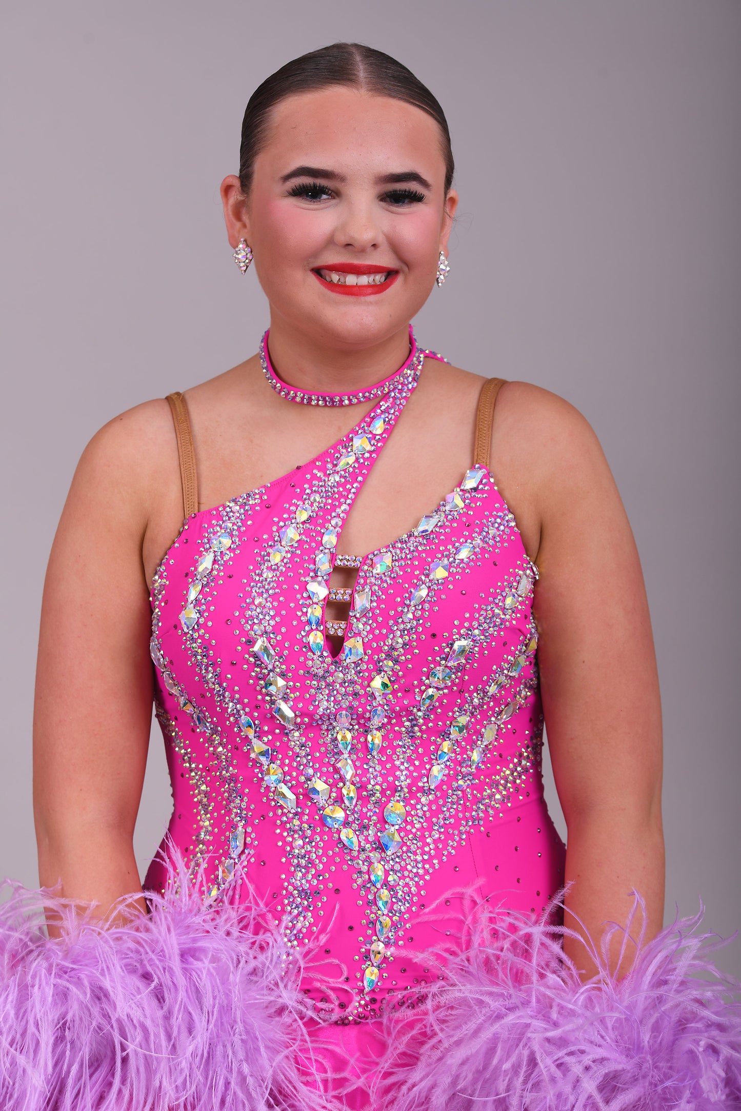005 Cerise Pink Competition Ballroom Dance Dress. Heavily stoned in AB and Fuchsia & lilac. Comes with ostrich cuffs in Lilac & Cerise. Beautiful back detail.