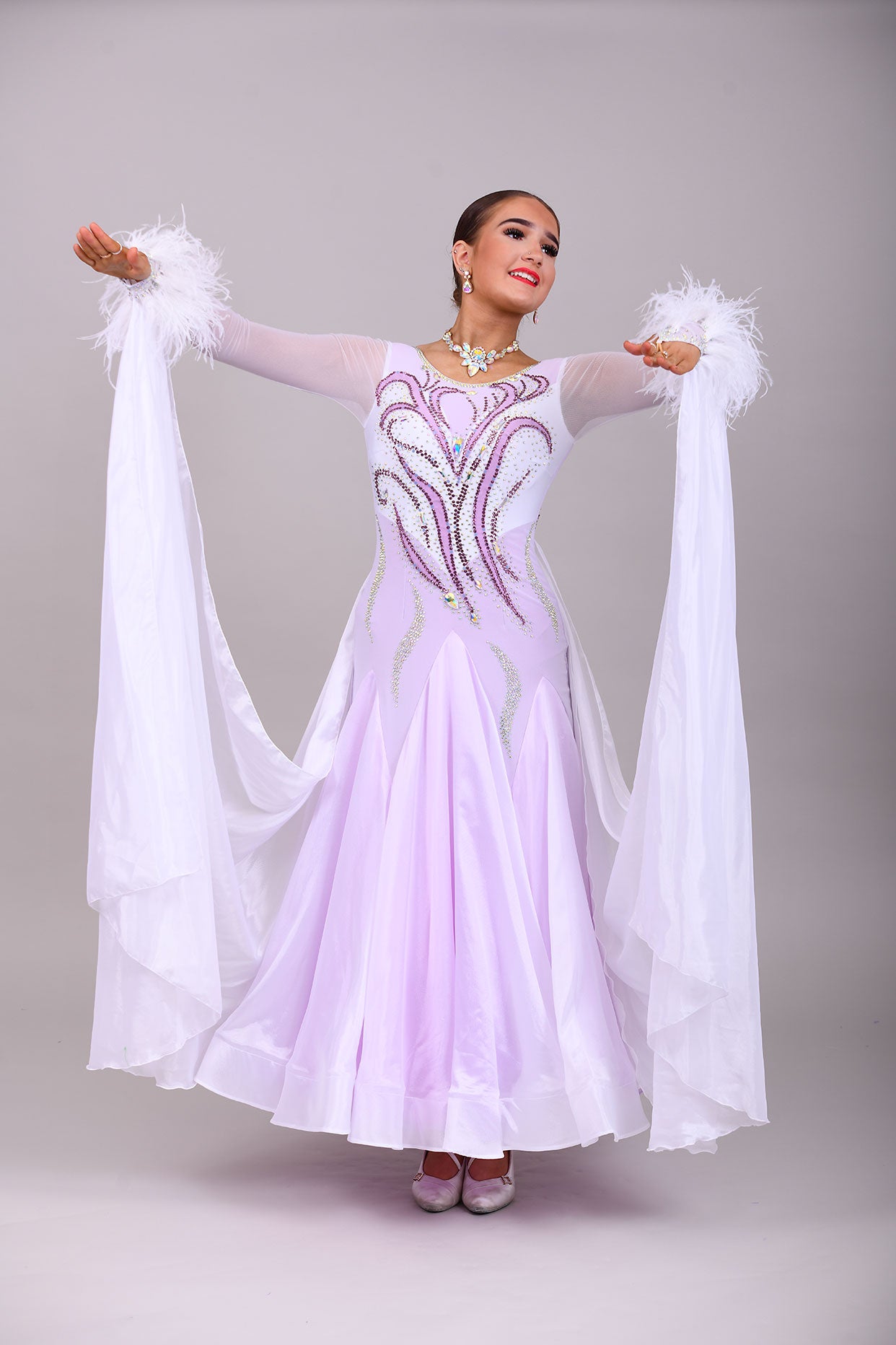 233 White Dress with lilac underlayer to the skirt. White floats. Decorated in lilac & AB stones with ostrich feather detail to the cuffs