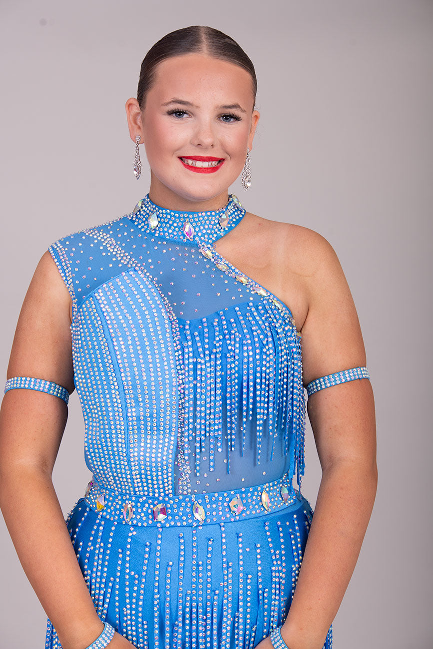 134L BUDGET (24) Blue Competition Latin Dance Dress. Stoned fabric strip detail throughout with 3D feature yo upper chest. Stoned in AB ❤️Showroom Appointments Available❤️