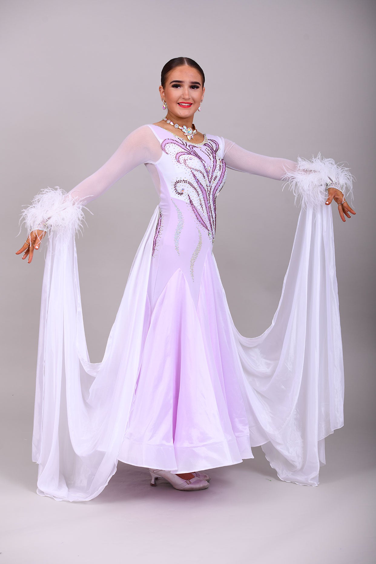 233 White Dress with lilac underlayer to the skirt. White floats. Decorated in lilac & AB stones with ostrich feather detail to the cuffs