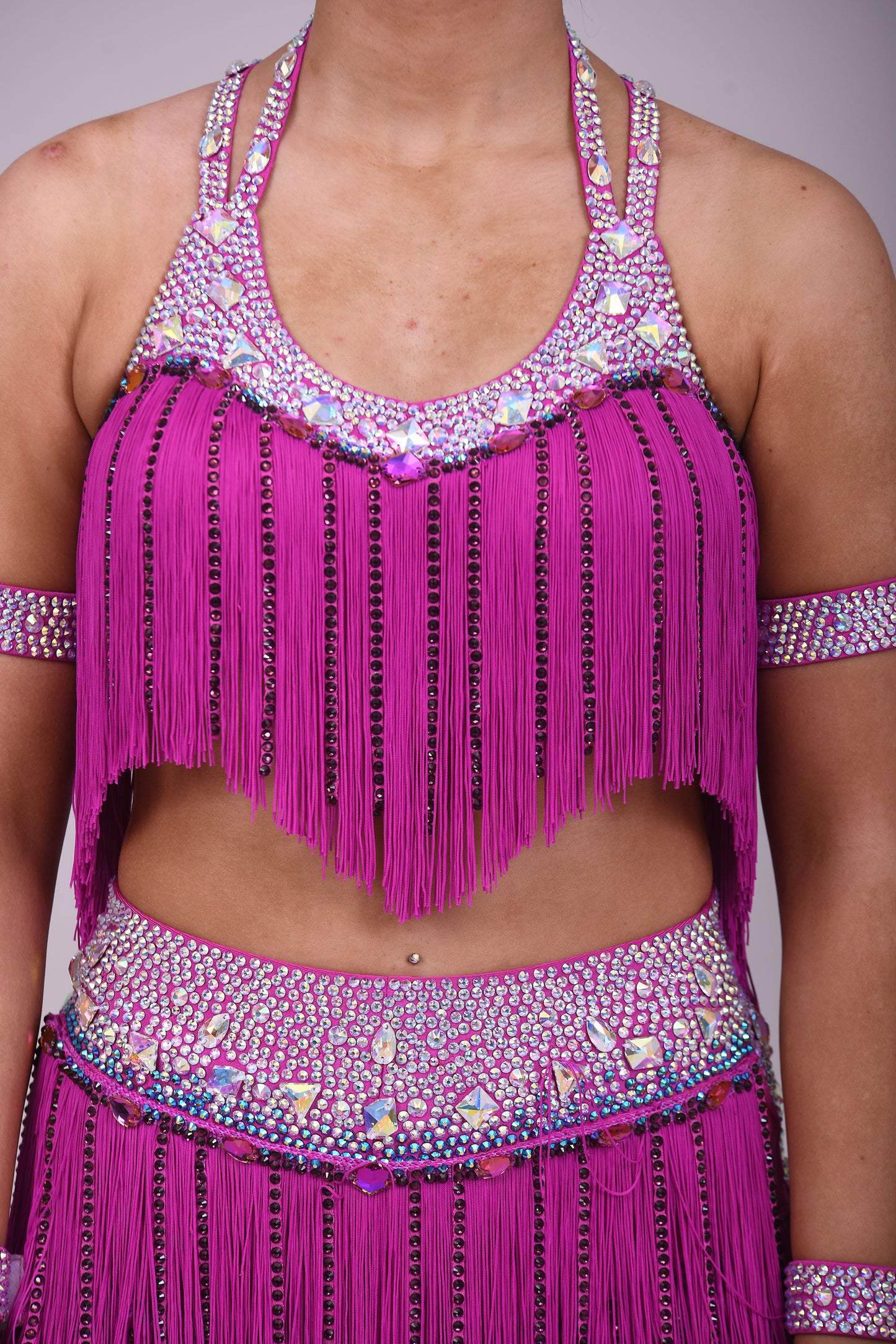 184 Fuschia Pink Latin 2 Piece. Very full fringed skirt and top. Stoned in Amethyst, AB & Aquamarine AB. Shorts attached under skirt