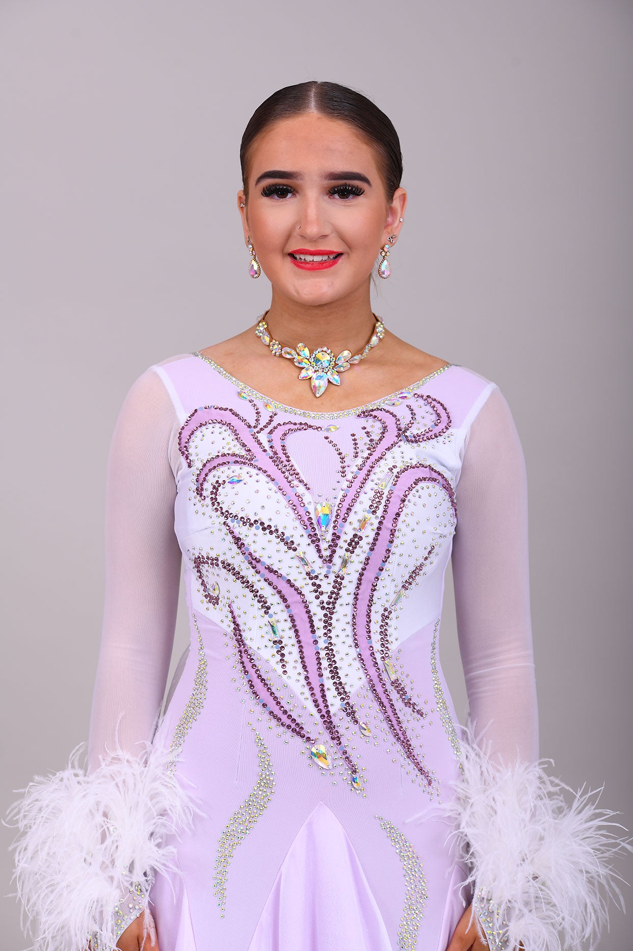 233 White Dress with lilac underlayer to the skirt. White floats. Decorated in lilac & AB stones with ostrich feather detail to the cuffs