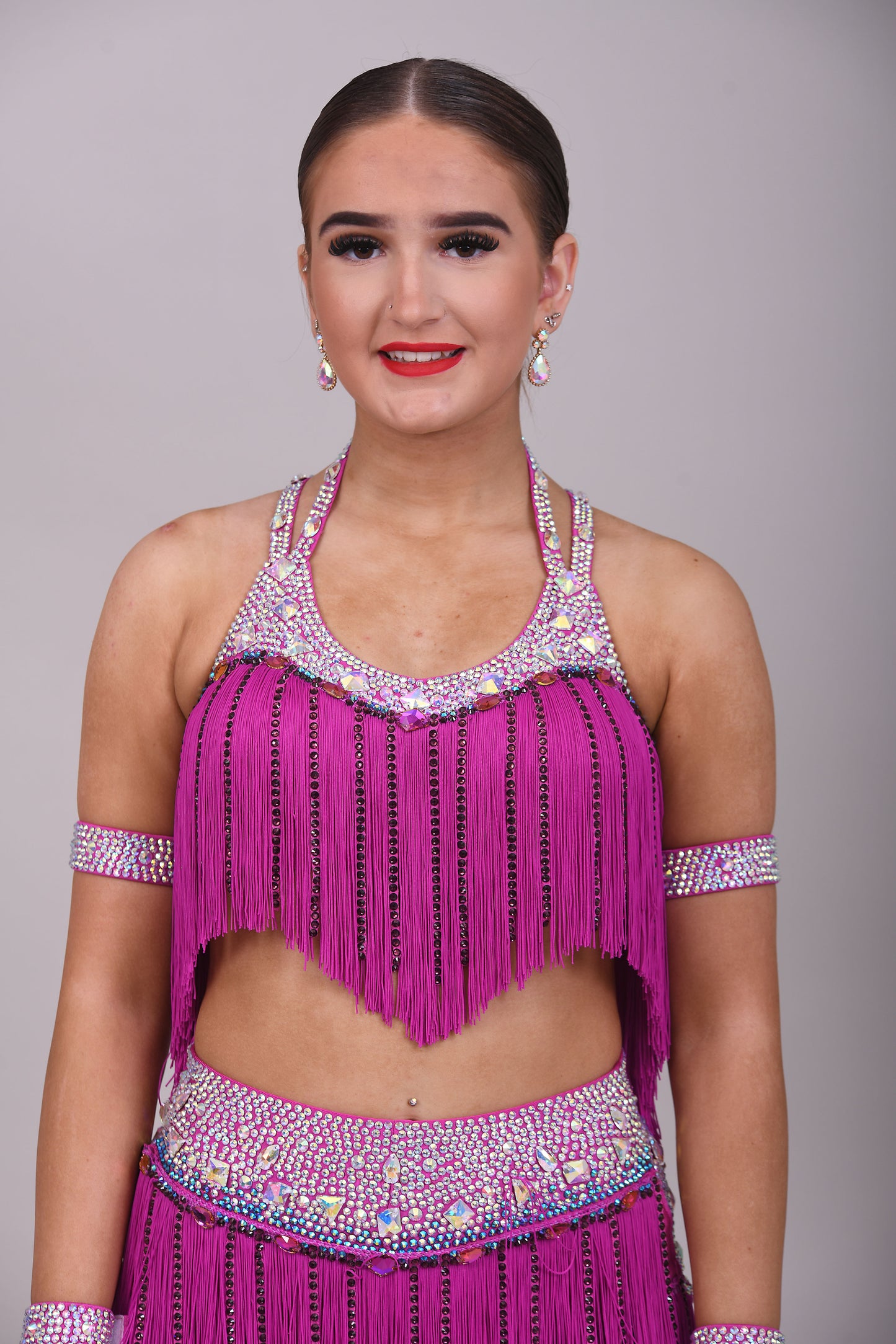 184 Fuschia Pink Latin 2 Piece. Very full fringed skirt and top. Stoned in Amethyst, AB & Aquamarine AB. Shorts attached under skirt