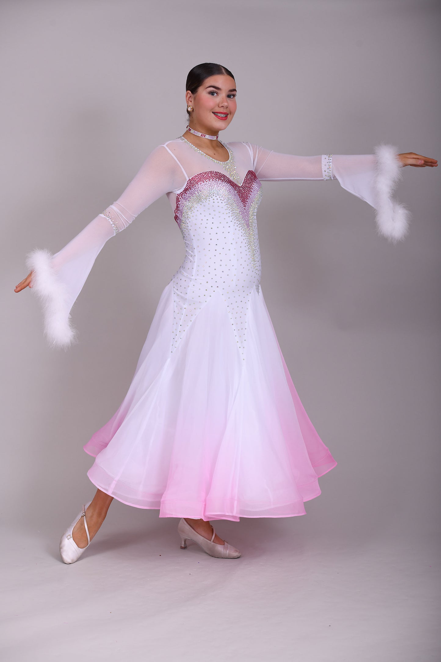 207 Pale Pink & White Ombré Ballroom Dress. Scoop neck & High mesh back. Feature stoning at the chest in rose, light rose & AB. Feather detailing to bell sleeves.