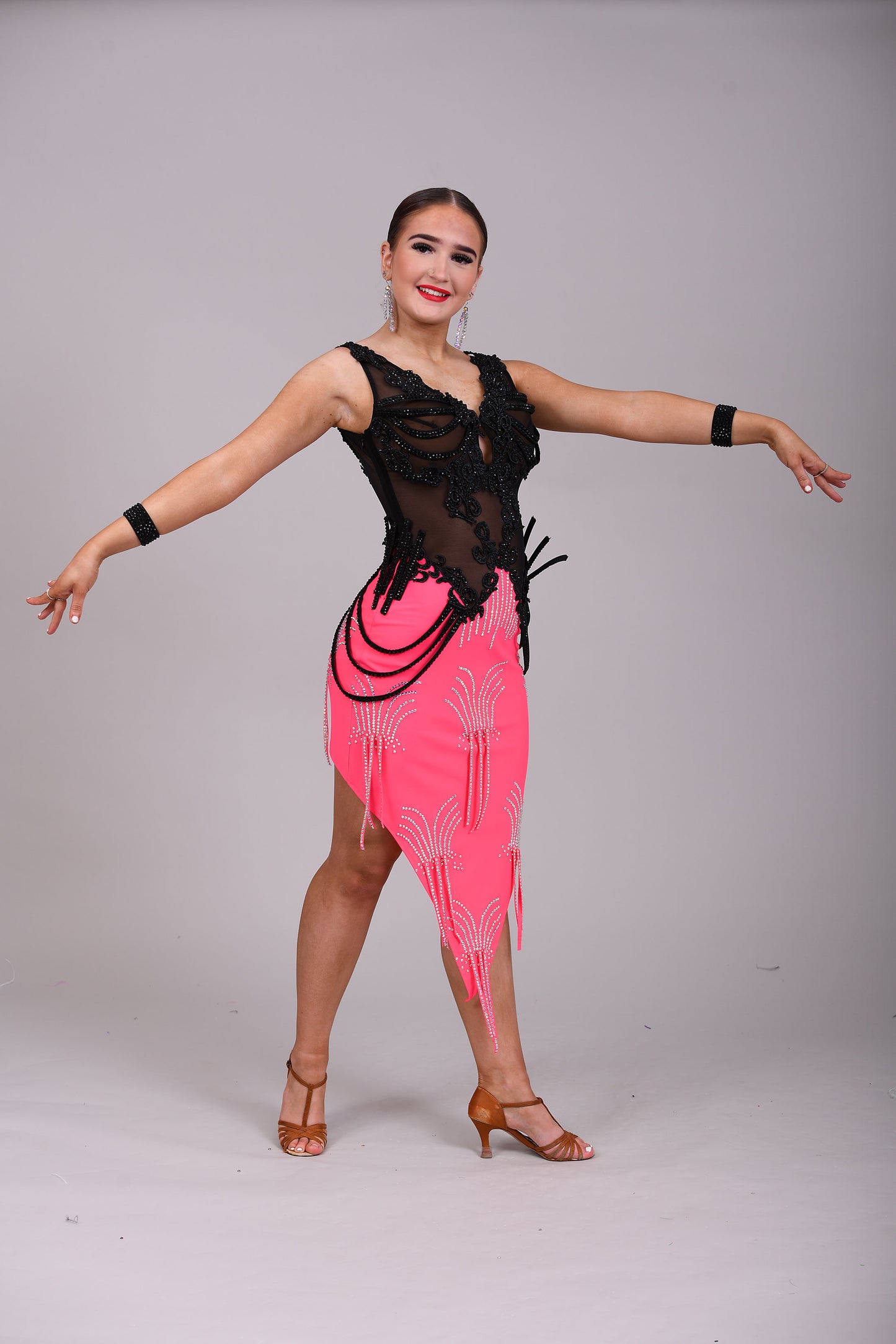084 Black & Electric Pink Latin Dress. Black mesh bodice decorated with black appliqué & jet stones. Stoned material hip straps. Skirt decorated in AB