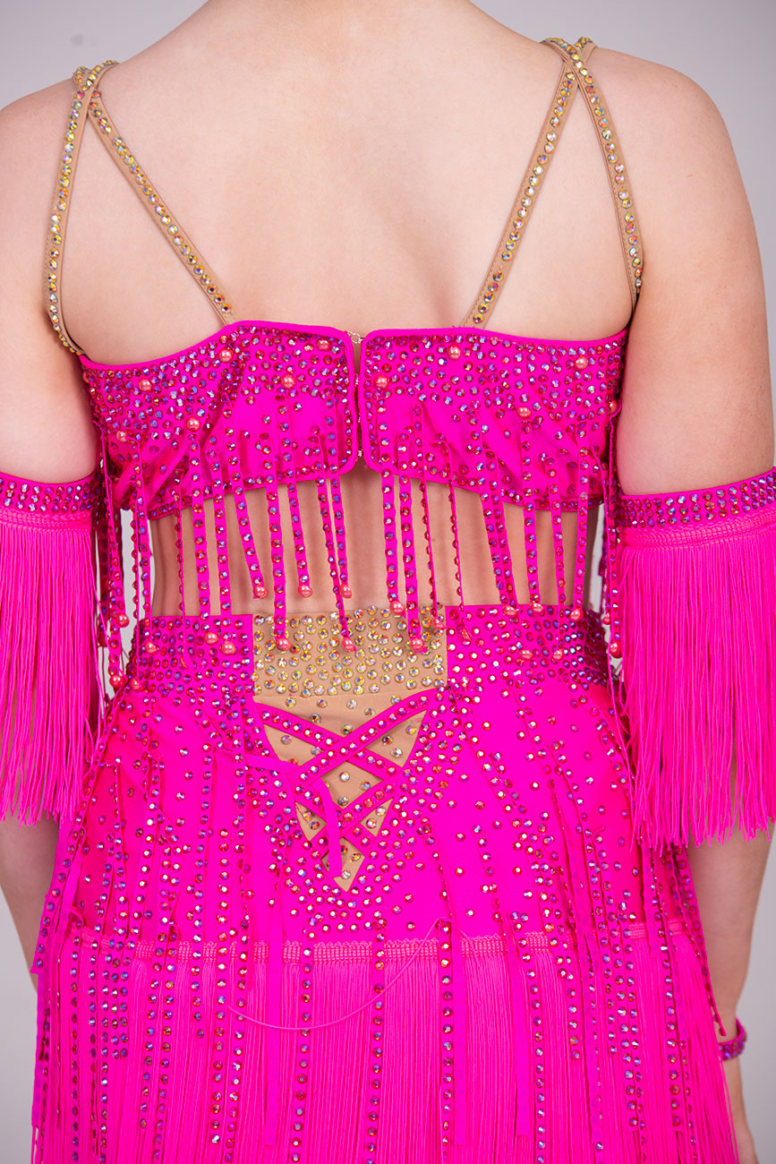 (BUDGET)11 Rose Pink Competition Latin Dance Dress. Flower detail to the chest & Hip. Fringed skirt with open side detail. Fringed arm cuffs & detailed necklace. Joined by crossover straps