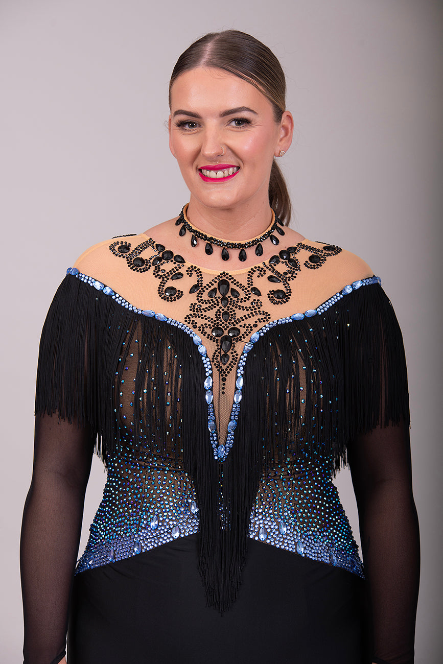 279 Black Competition Latin Dress. Stoned in Sapphire AB & Jet stones. Off the shoulder effect mesh. Black fringe detail to front & back. Full frill skirt giving lovely movement.