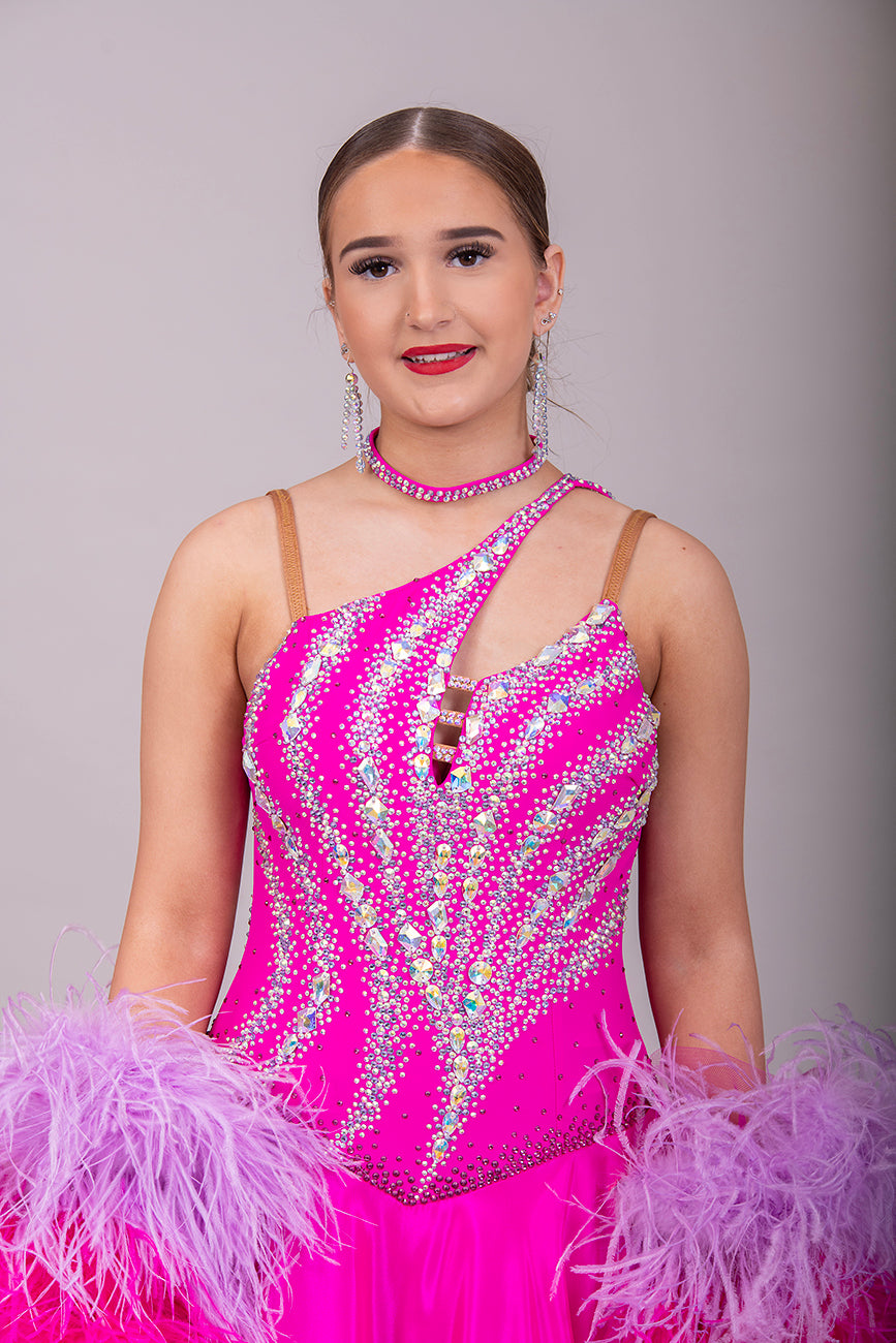 005 Cerise Pink Competition Ballroom Dance Dress. Heavily stoned in AB and Fuchsia & lilac. Comes with ostrich cuffs in Lilac & Cerise. Beautiful back detail.