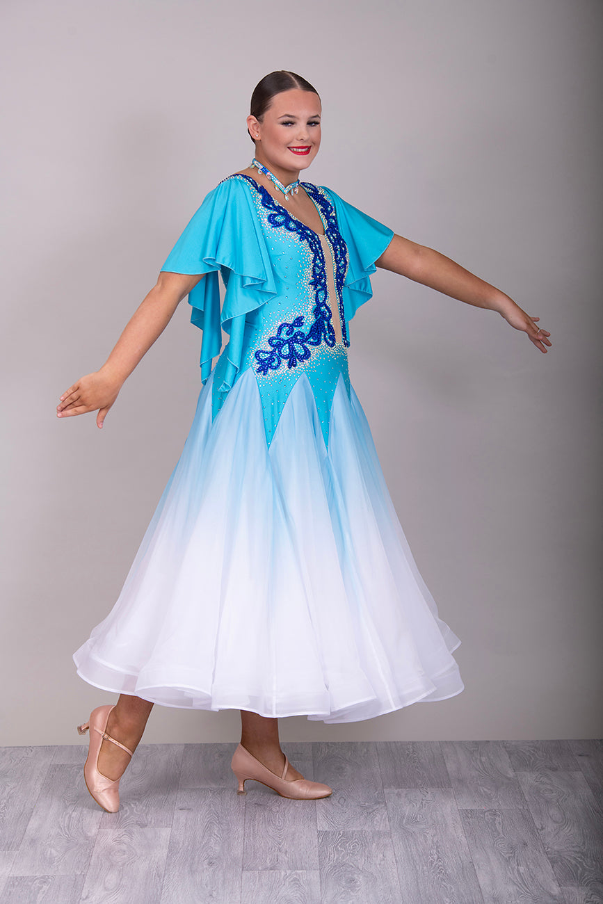 034 Turquoise & White ombré Ballroom Dress. Feature floaty sleeves & flesh panel detail to the chest. Decorated with royal blue motifs. Stoned in sapphire, light sapphire & AB