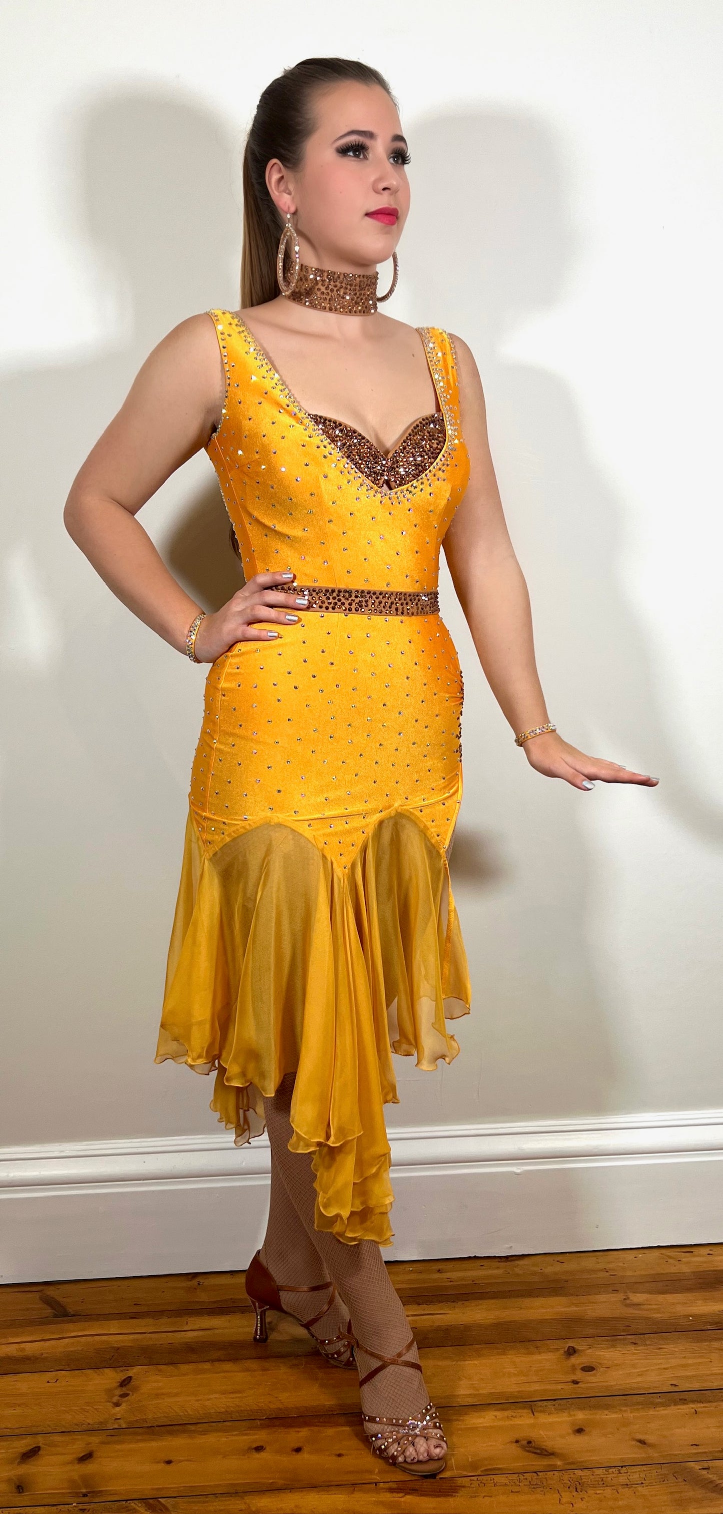 044 Bright Gold Latin Dress. Fully stoned bra feature with separate belt. Chiffon handkerchief skirts with ruching side detail. Stoned in topaz & sunshine yellow.