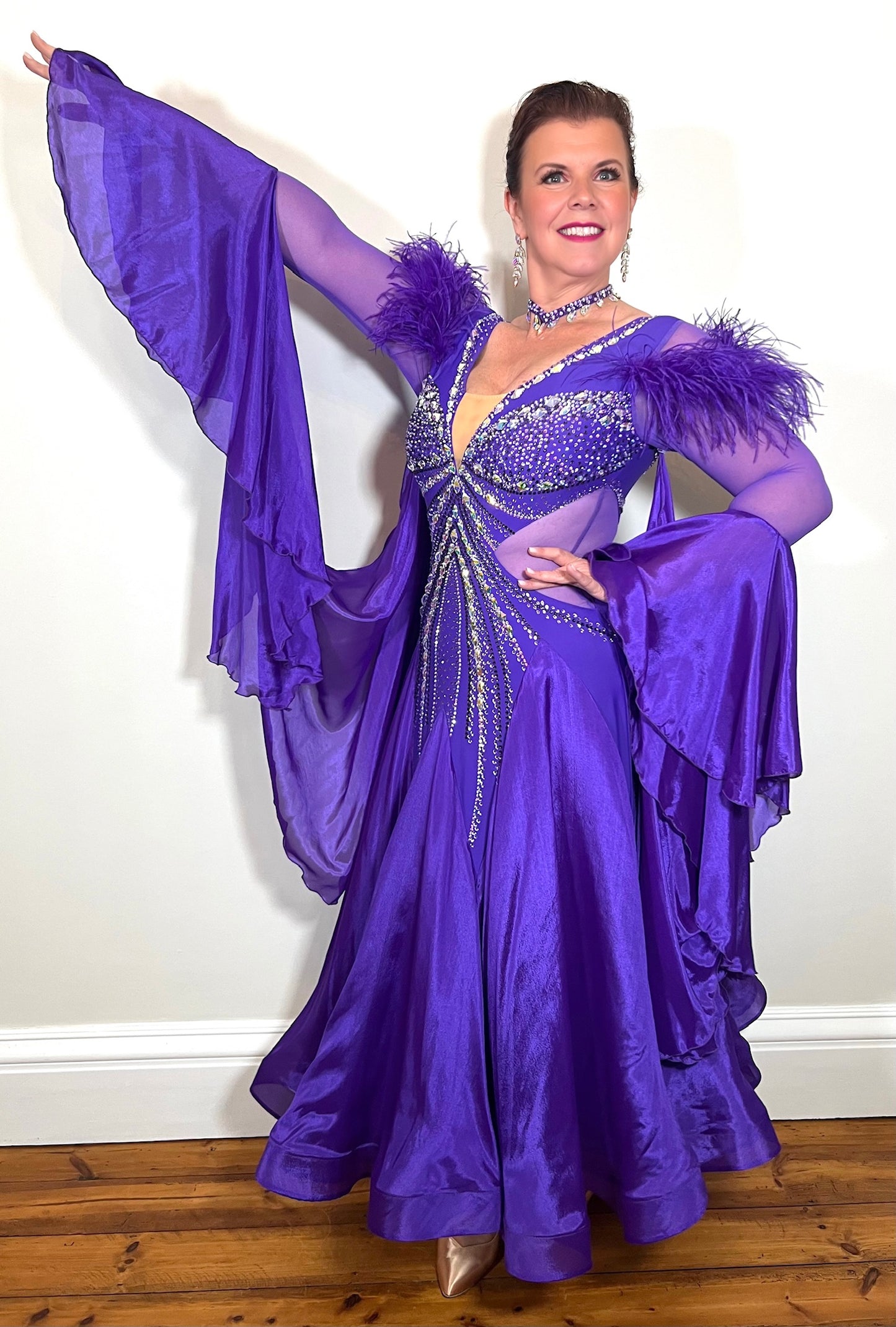 287 Stunning Purple Ballroom Dance Dress. Ostrich feather detail to the upper arm with floaty sleeves from the elbow(finger loop can be added). High back for wearing own bra. Stoned in AB, light Amethyst & Amethyst.