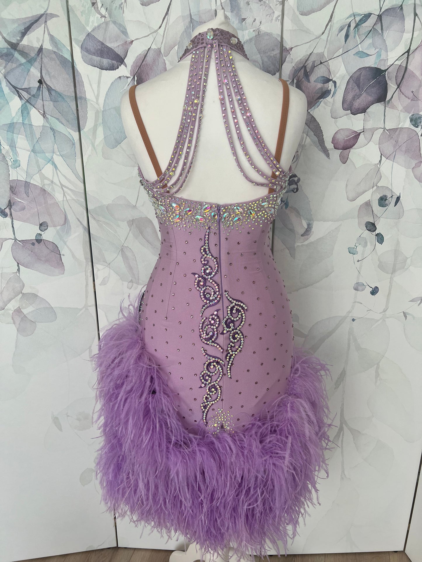 344 Lilac Latin Dress with keyhole halter neck detail. Strapping design on back. Lilac ostrich feather boa skirt. Decorated with purple motif. Stoned in green & AB