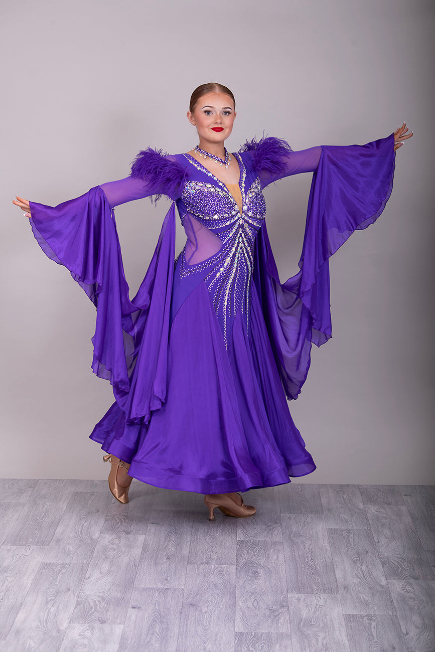 287 Stunning Purple Ballroom Dance Dress. Ostrich feather detail to the upper arm with floaty sleeves from the elbow(finger loop can be added). High back for wearing own bra. Stoned in AB, light Amethyst & Amethyst.