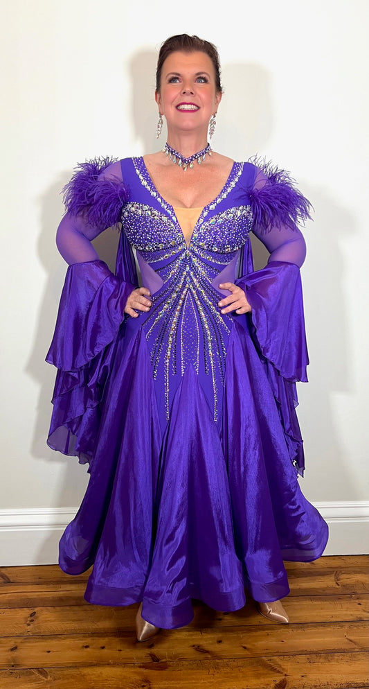 287 Stunning Purple Ballroom Dance Dress. Ostrich feather detail to the upper arm with floaty sleeves from the elbow(finger loop can be added). High back for wearing own bra. Stoned in AB, light Amethyst & Amethyst.