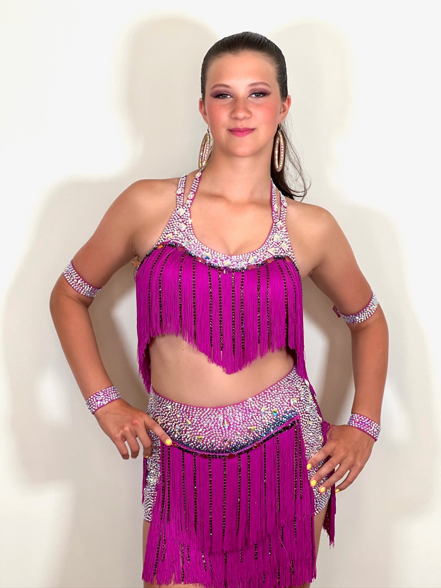 184 Fuschia Pink Latin 2 Piece. Very full fringed skirt and top. Stoned in Amethyst, AB & Aquamarine AB. Shorts attached under skirt