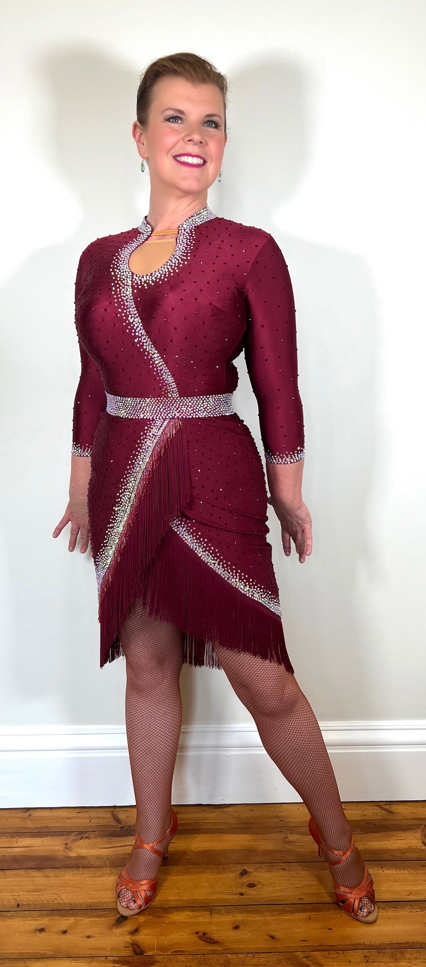 074 Wine Red Latin Dance Dress. Wine bead fringe & tassel fringe feature to the skirt. Stoned in AB & Wine red with mid tan mesh keyhole panel to the front. Optional Belt.