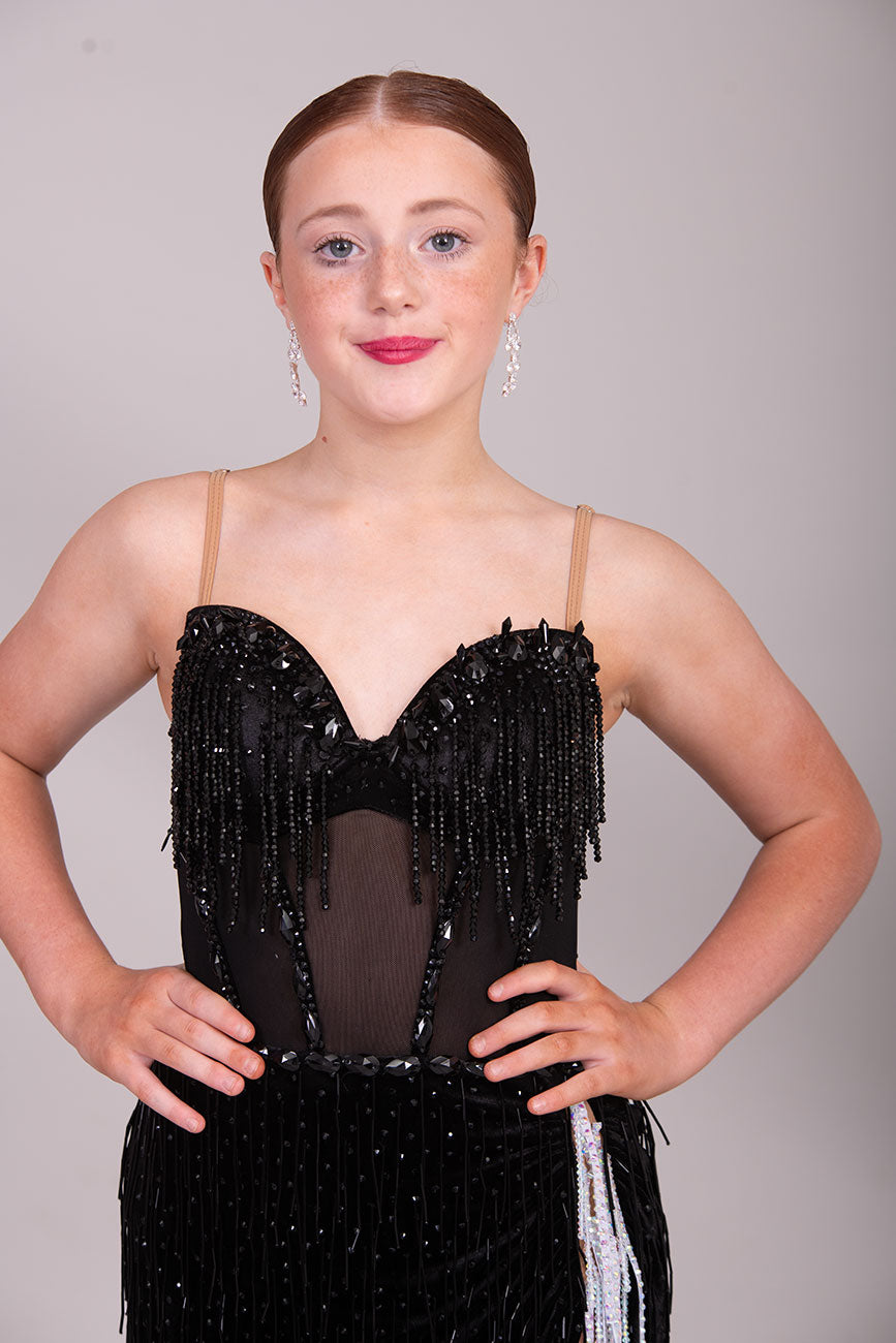 (BUDGET)12 Black Competition Latin Dance Dress. Heavily stoned bodice with beaded tassels. Mesh centre panel with corset details. Asymmetrical skirt stoned & full of beaded tassels. Open back with flesh security straps