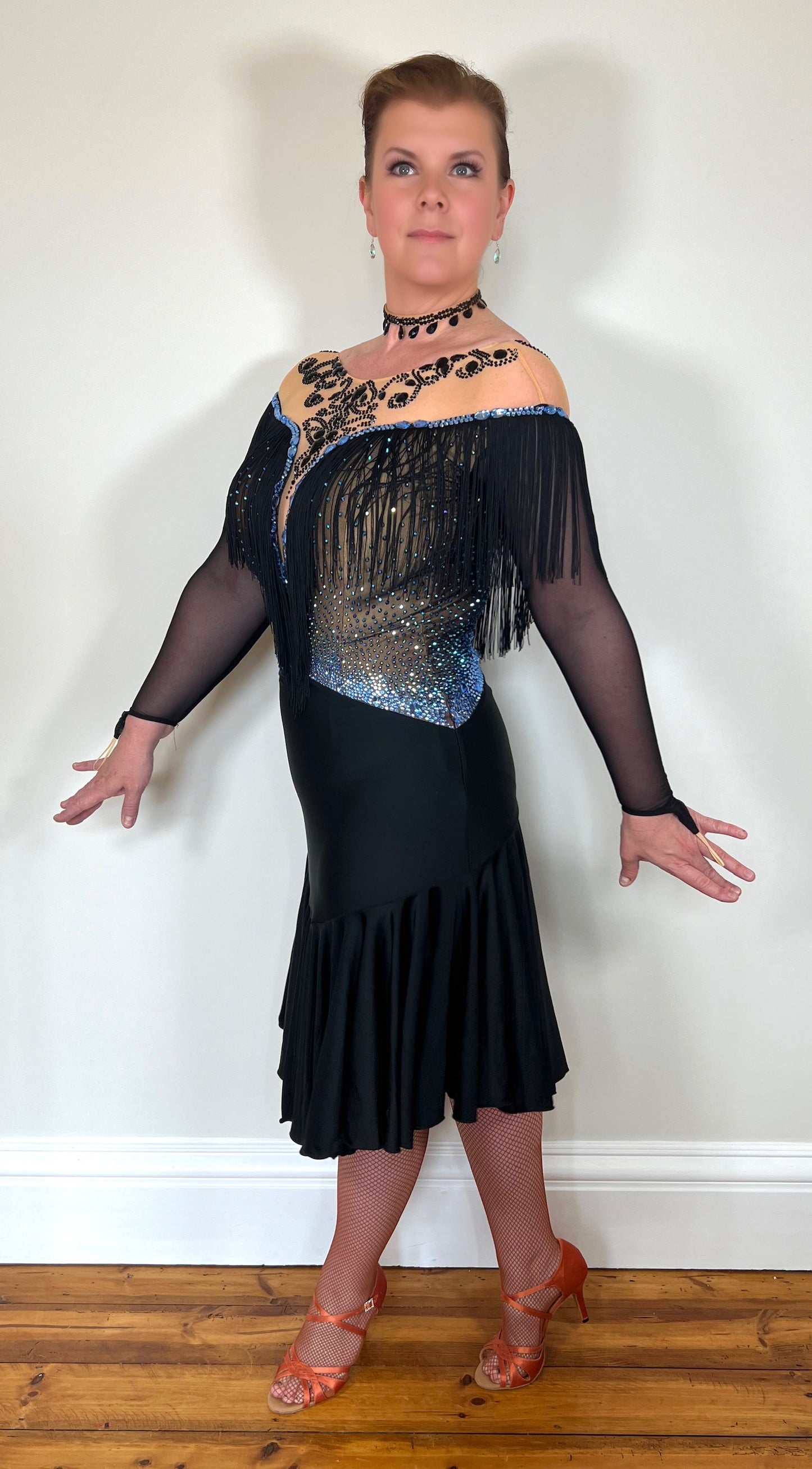 0012 Black Competition Latin Dress. Stoned in Sapphire AB & Jet stones. Off the shoulder effect mesh. Black fringe detail to front & back. Full frill skirt giving lovely movement.