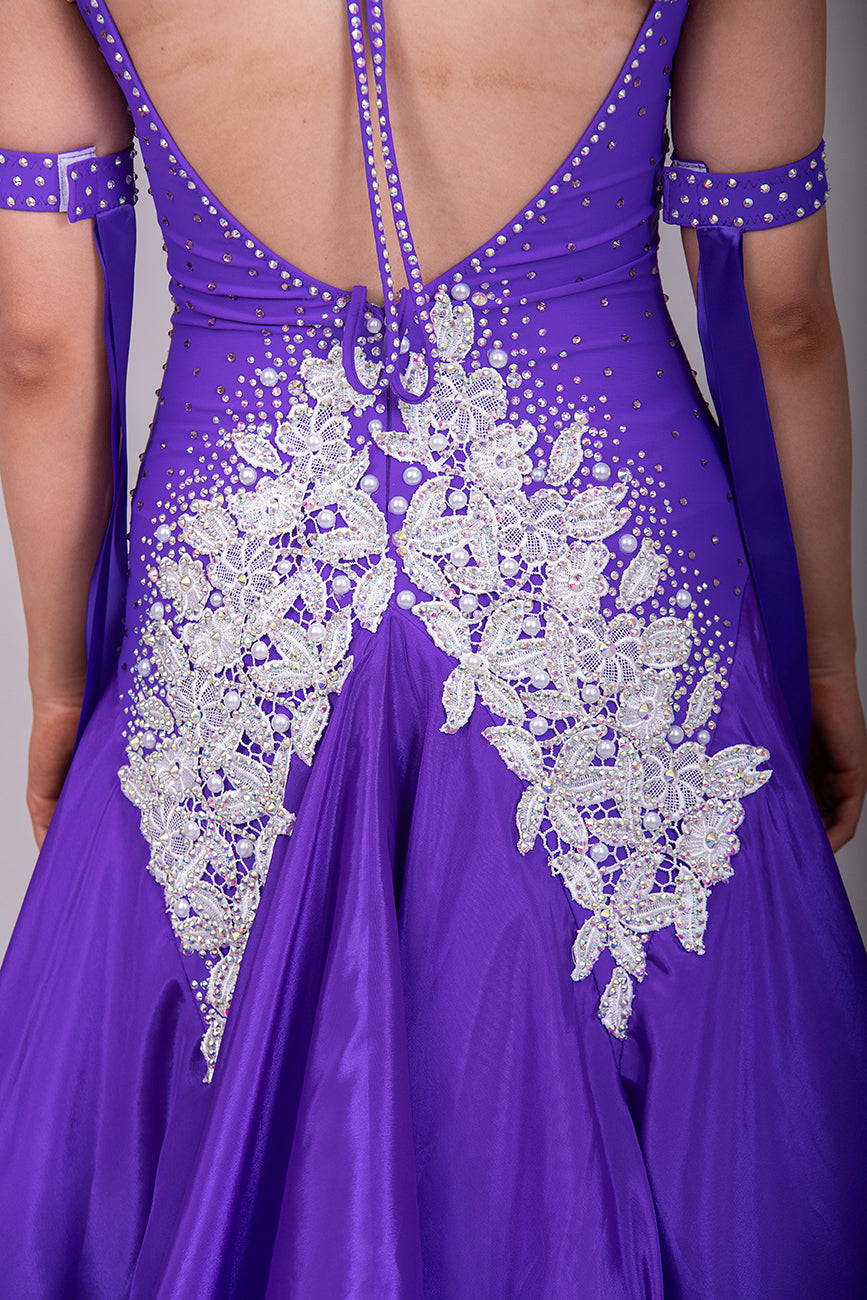 056 Purple Halter Neck Ballroom Dress. White lace detail front/back bodice. Purple fishnet panel on front. Decorated in purple & AB stones. Underskirts in White with exposed satin skirts to one side