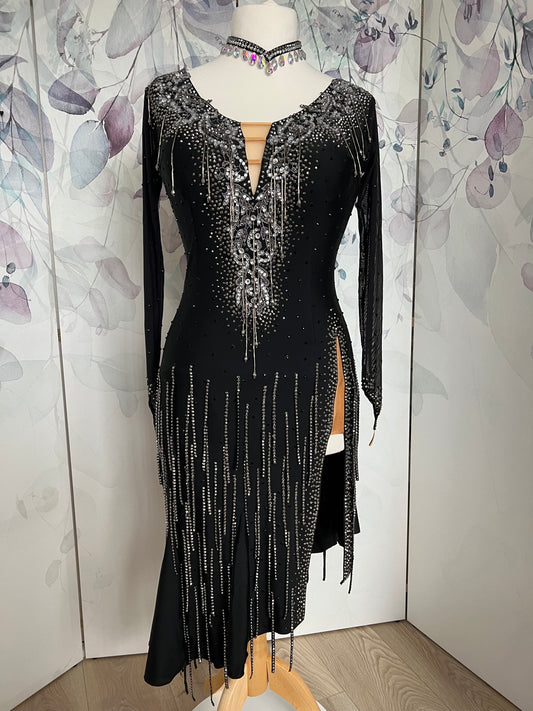 147 Striking Black Latin Dress. Silver motif stoned in Crystal & Jet Hematite with silver bead droppers. Split to 1 side of the skirt. Stoned fringing all over the skirt in Jet Hematite.