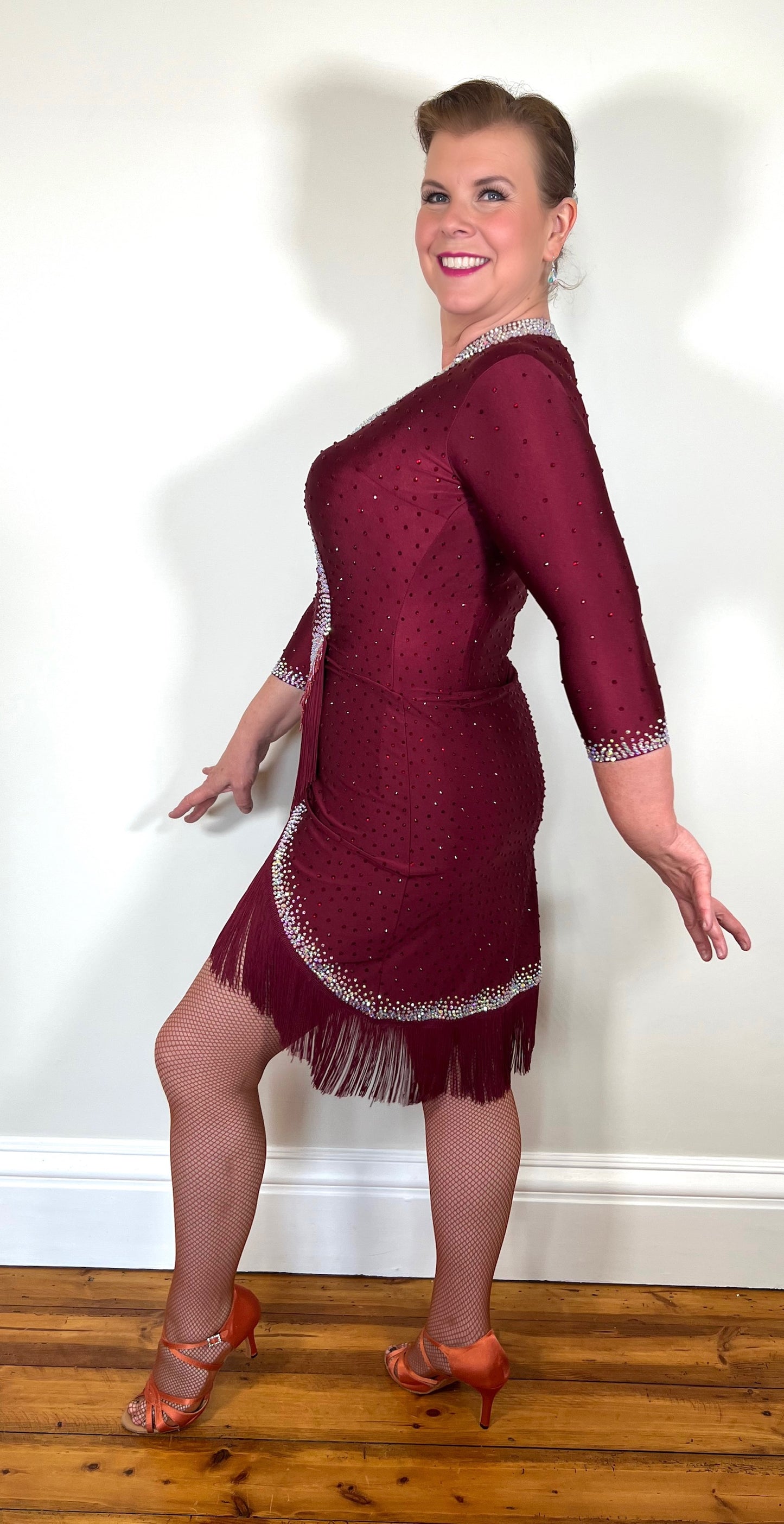 074 Wine Red Latin Dance Dress. Wine bead fringe & tassel fringe feature to the skirt. Stoned in AB & Wine red with mid tan mesh keyhole panel to the front. Optional Belt.