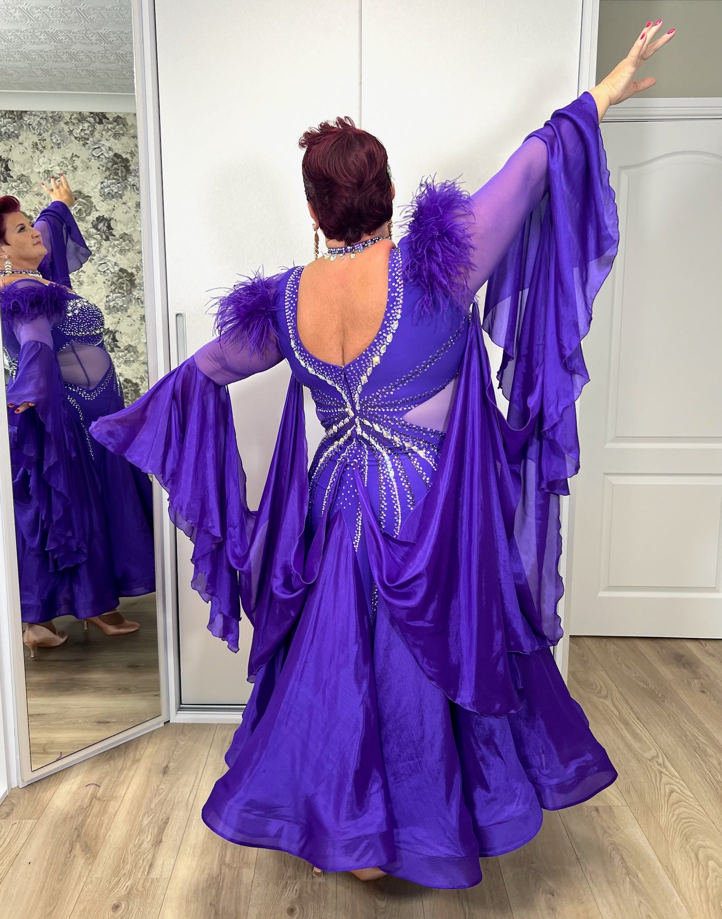 287 Stunning Purple Ballroom Dance Dress. Ostrich feather detail to the upper arm with floaty sleeves from the elbow(finger loop can be added). High back for wearing own bra. Stoned in AB, light Amethyst & Amethyst.