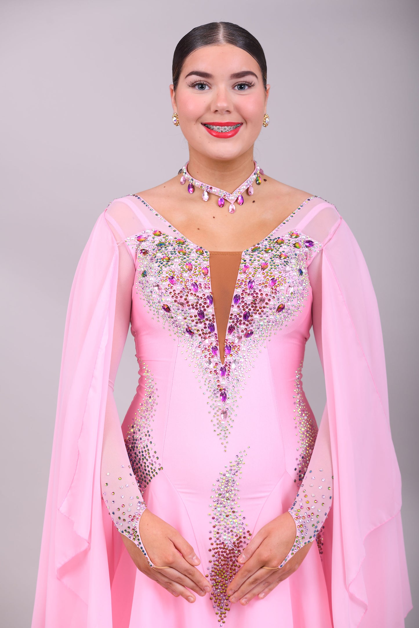 131 Pink Ballroom Dress with shoulder floats. Tan panel to the chest area giving a plunging neckline effect. Decorated in AB & Fuchsia stones