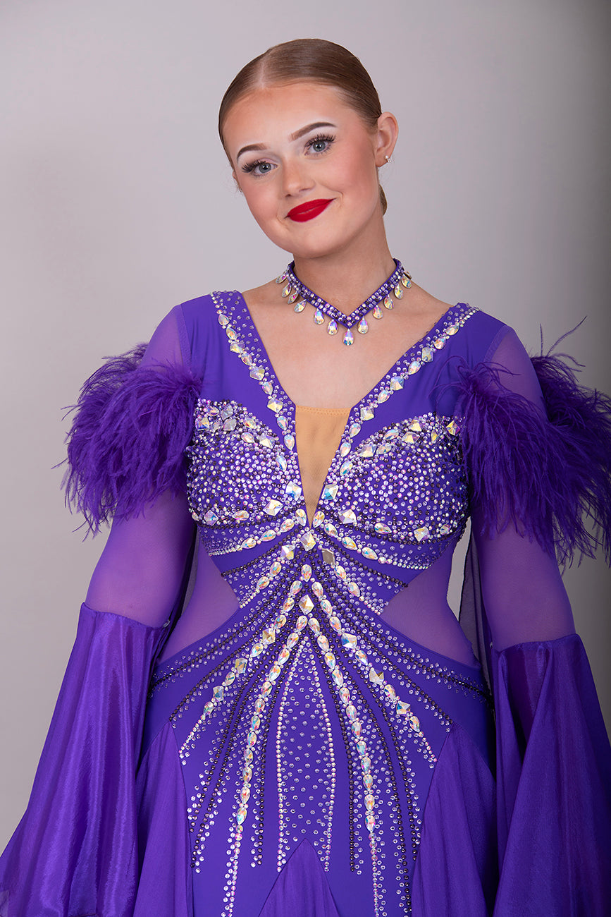287 Stunning Purple Ballroom Dance Dress. Ostrich feather detail to the upper arm with floaty sleeves from the elbow(finger loop can be added). High back for wearing own bra. Stoned in AB, light Amethyst & Amethyst.