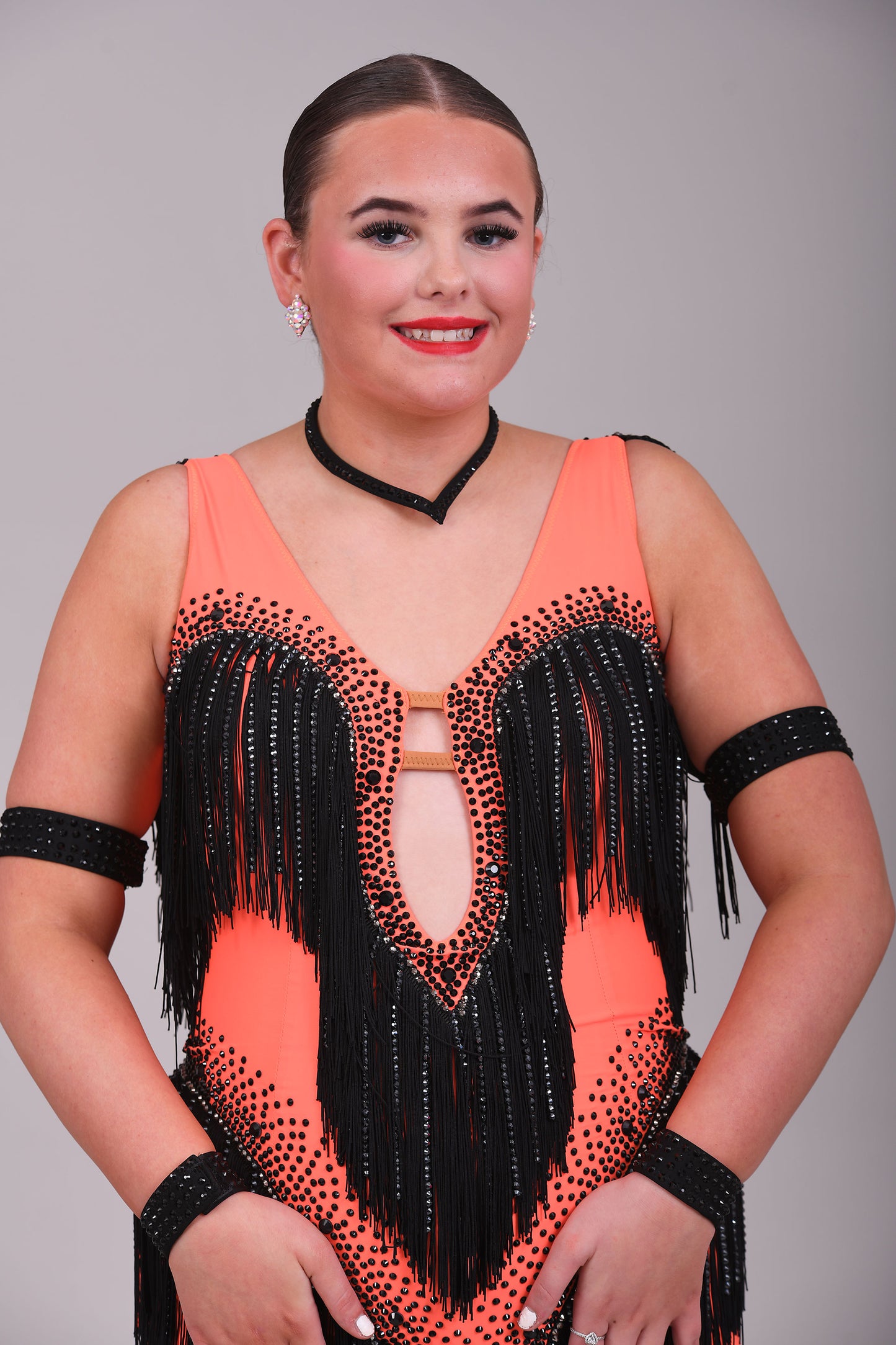 133 Flo Orange Latin dress with black fringe detailing. Plunge neckline. Material droppers stoned in hematite in amongst the fringing. Jet stones.