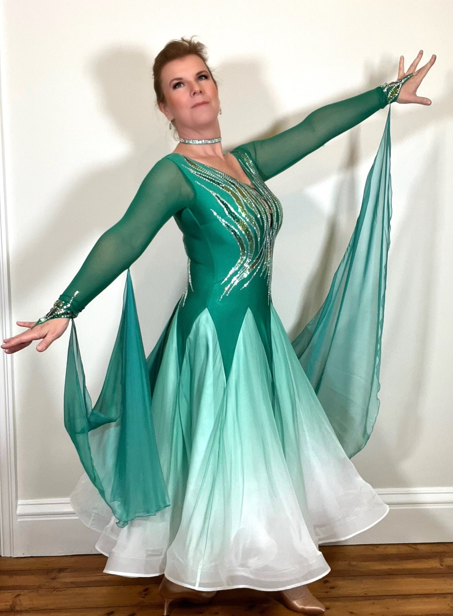 204 Green to White Ombré Ballroom dress. Strappy detail to the chest with flesh panel to the back. Green floats attached to the arms & back. Stoned with peridot, Emerald & AB.
