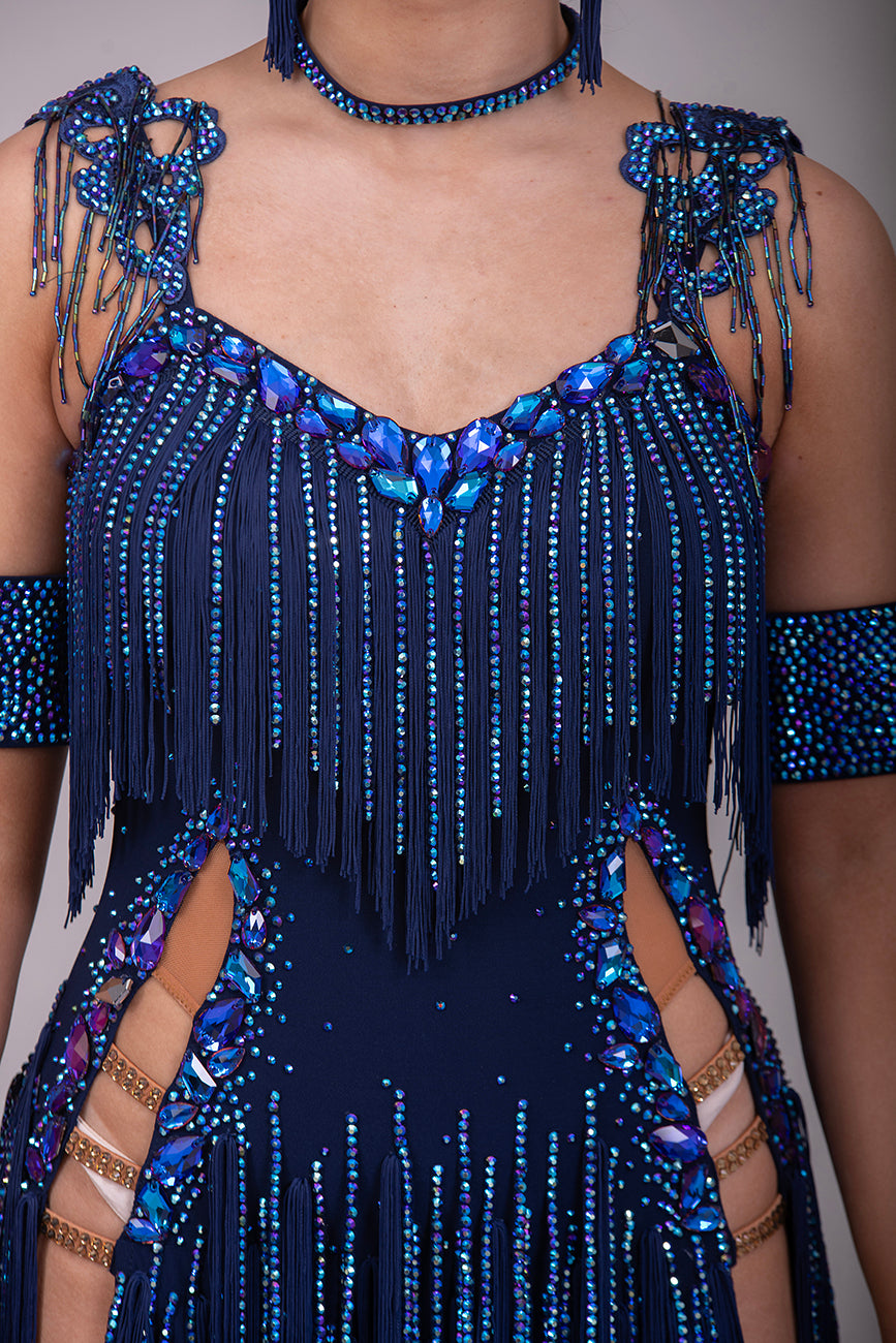 14L Navy Blue Competition Latin/Rhythm Dress. Stoned Fabric Tassels for the Skirt & Upper Chest. Heavily Stoned in Blue AB & Blue. Strappy detailing to the Hips & Drape to the back