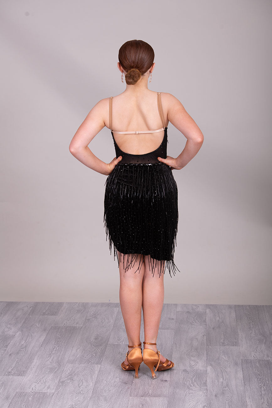 (BUDGET)12 Black Competition Latin Dance Dress. Heavily stoned bodice with beaded tassels. Mesh centre panel with corset details. Asymmetrical skirt stoned & full of beaded tassels. Open back with flesh security straps