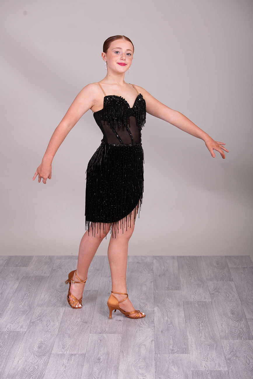 (BUDGET)12 Black Competition Latin Dance Dress. Heavily stoned bodice with beaded tassels. Mesh centre panel with corset details. Asymmetrical skirt stoned & full of beaded tassels. Open back with flesh security straps