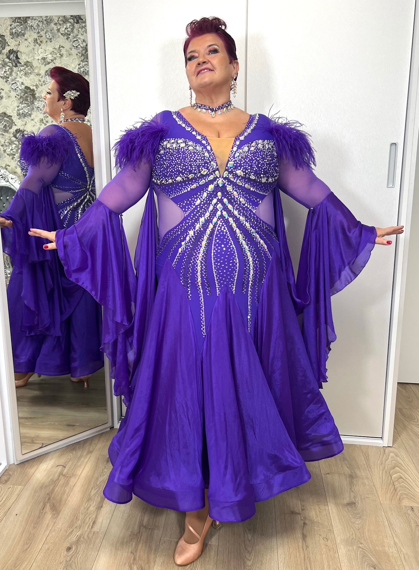 287 Stunning Purple Ballroom Dance Dress. Ostrich feather detail to the upper arm with floaty sleeves from the elbow(finger loop can be added). High back for wearing own bra. Stoned in AB, light Amethyst & Amethyst.