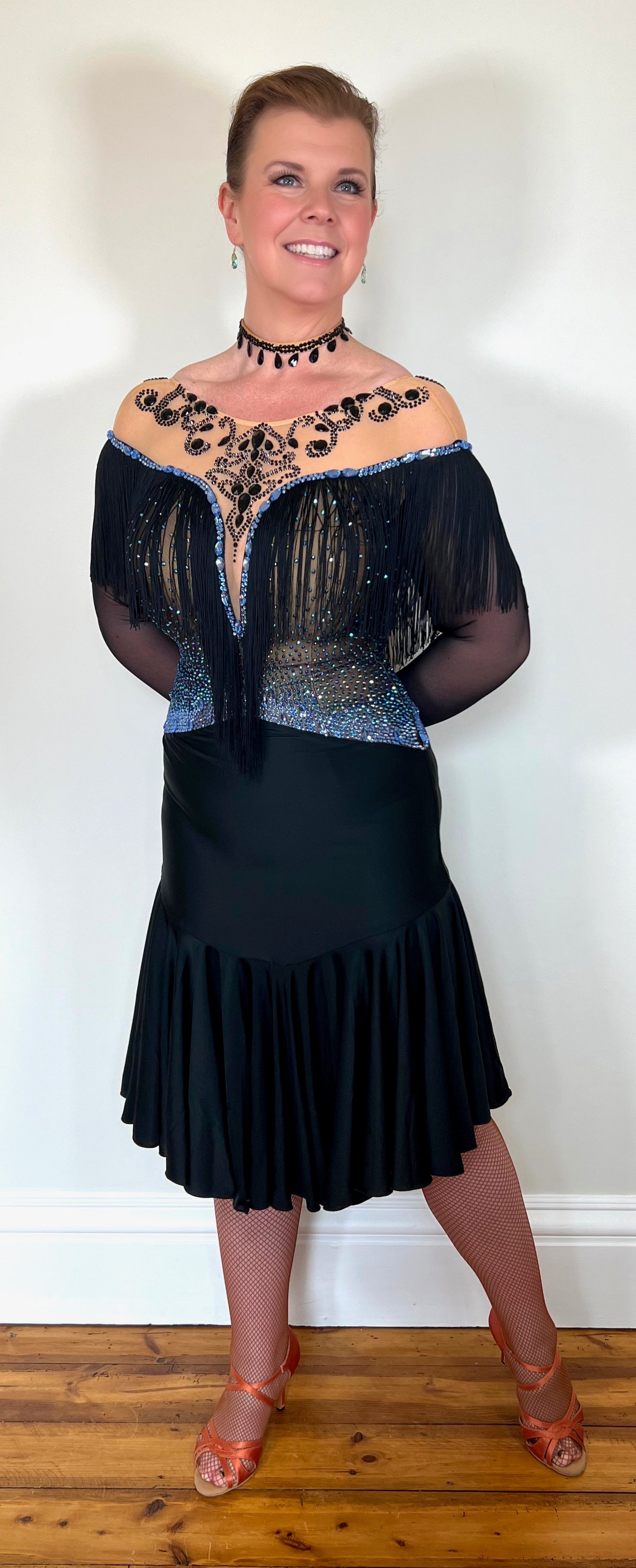0012 Black Competition Latin Dress. Stoned in Sapphire AB & Jet stones. Off the shoulder effect mesh. Black fringe detail to front & back. Full frill skirt giving lovely movement.