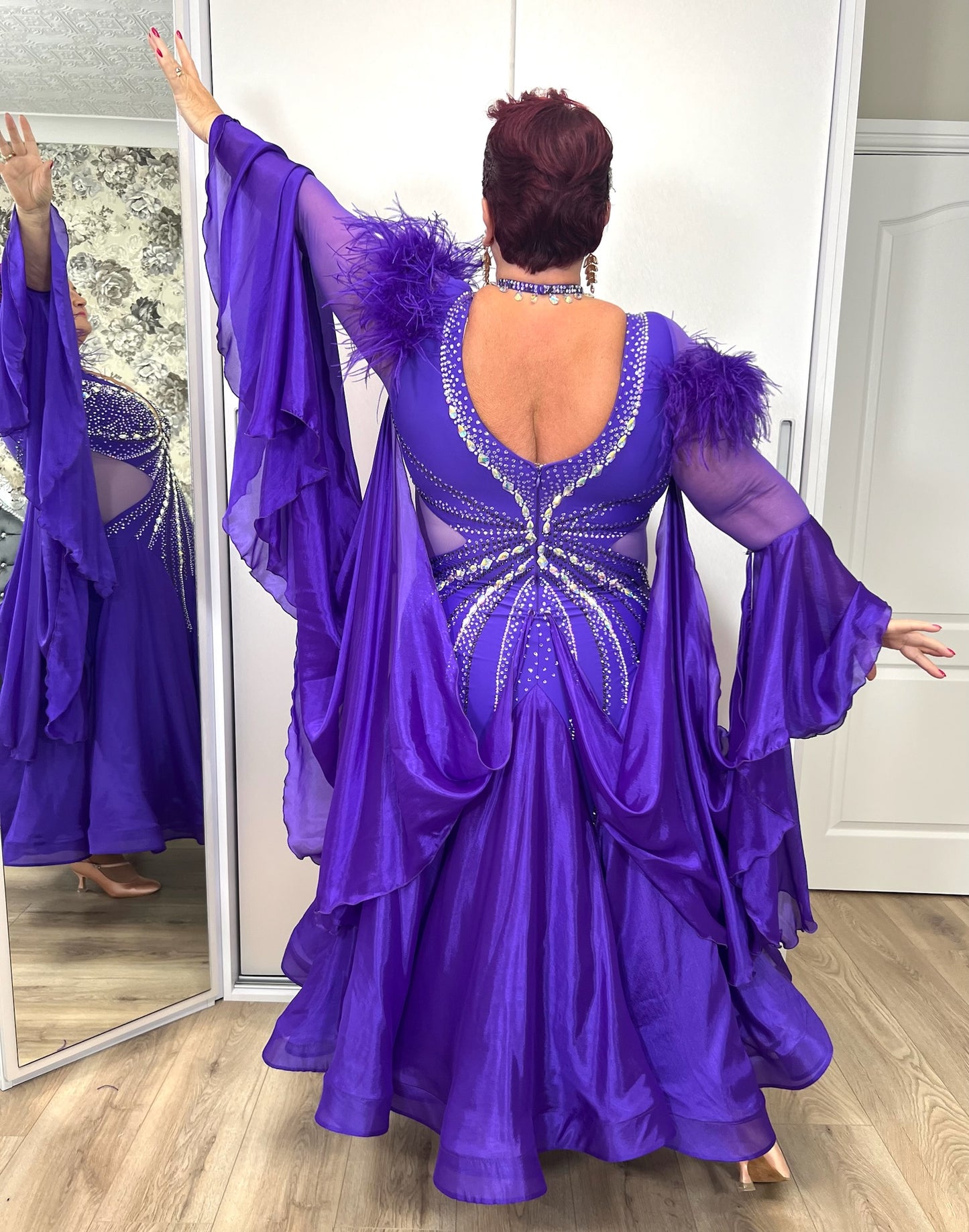 287 Stunning Purple Ballroom Dance Dress. Ostrich feather detail to the upper arm with floaty sleeves from the elbow(finger loop can be added). High back for wearing own bra. Stoned in AB, light Amethyst & Amethyst.