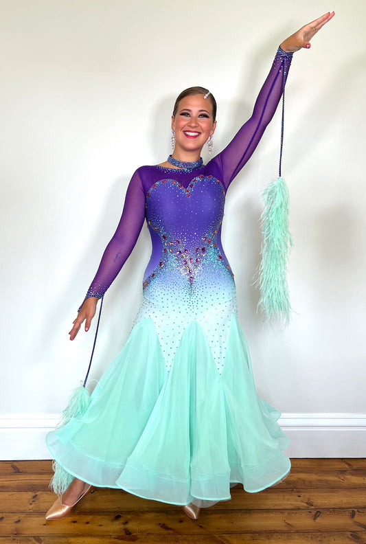 167 Ombré purple to mint green competition Ballroom dance dress. Stoned in mint green, mint green ab, purple & vitrail. Ostrich feather floats attached to stoned strips. High back to give the option of wearing own bra.