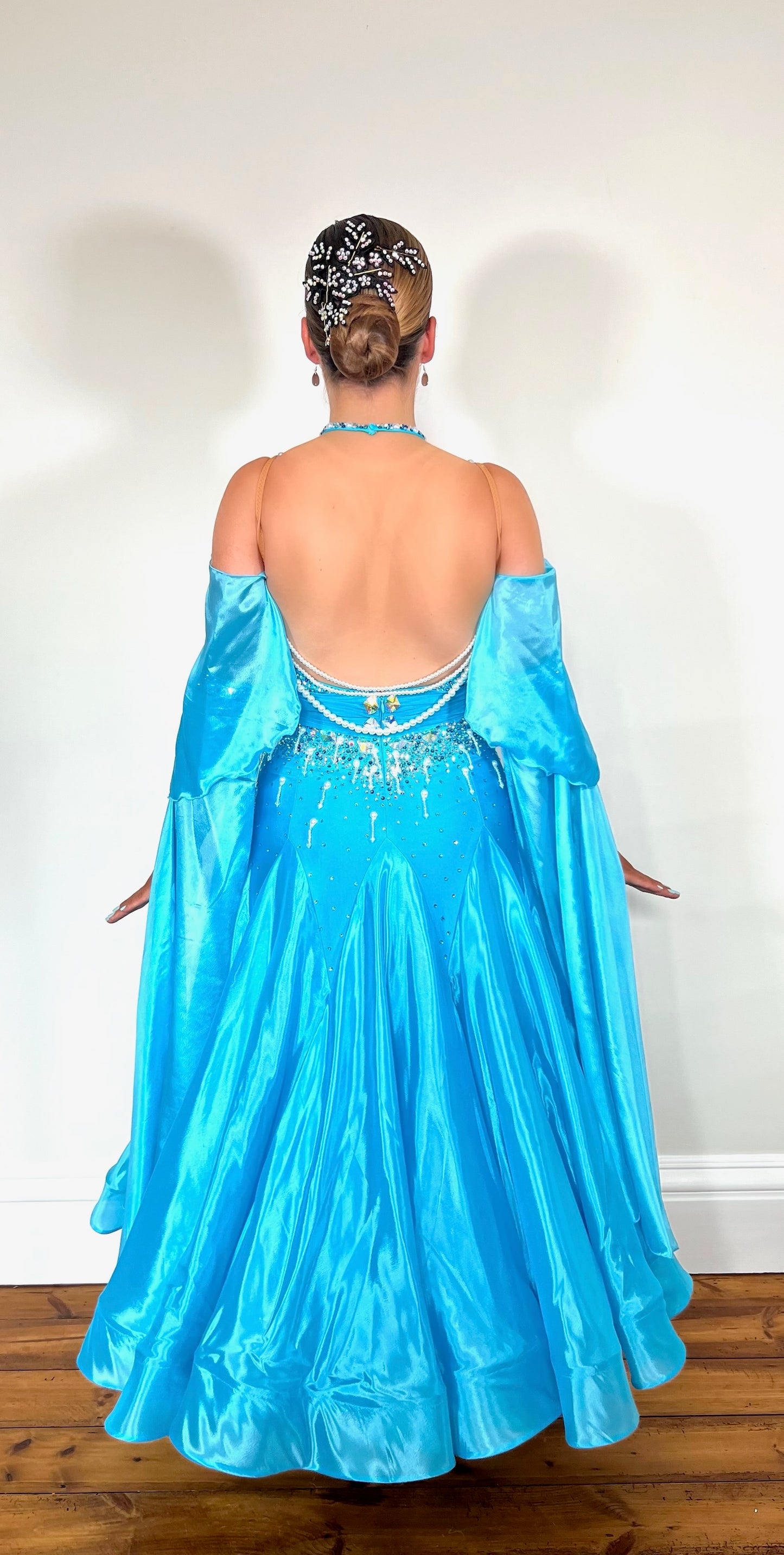 322 Paradise Blue Ballroom Dress with shoulder drapes. Comes with separate arm cuff floats. Decorated with Pearls, blue and AB stones. Detailed pearl strings to back