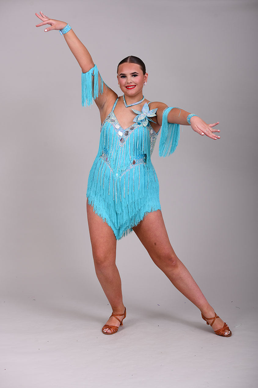 001 Turquoise Blue Competition Latin Dance Dress. Very full Fringes. 3D flower detail to the left shoulder. Cones with fringed armbands and bracelets. Decorated with silver mirrors & AB stones.
