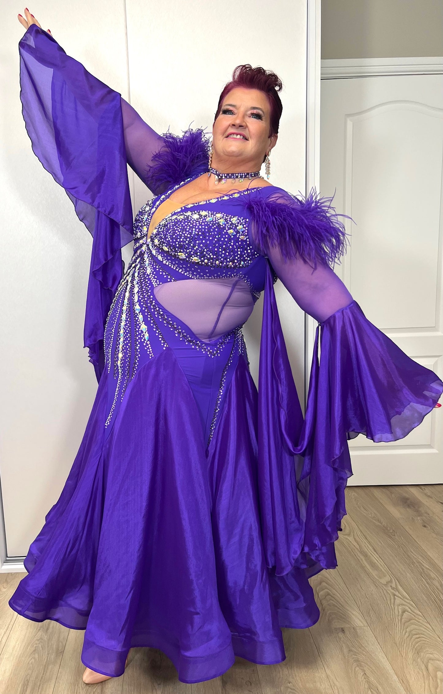 287 Stunning Purple Ballroom Dance Dress. Ostrich feather detail to the upper arm with floaty sleeves from the elbow(finger loop can be added). High back for wearing own bra. Stoned in AB, light Amethyst & Amethyst.