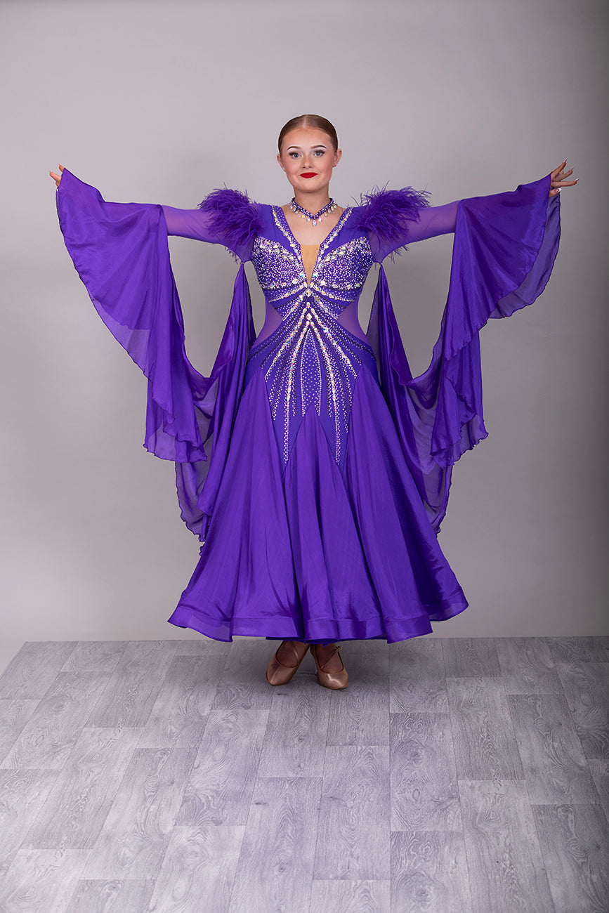 287 Stunning Purple Ballroom Dance Dress. Ostrich feather detail to the upper arm with floaty sleeves from the elbow(finger loop can be added). High back for wearing own bra. Stoned in AB, light Amethyst & Amethyst.