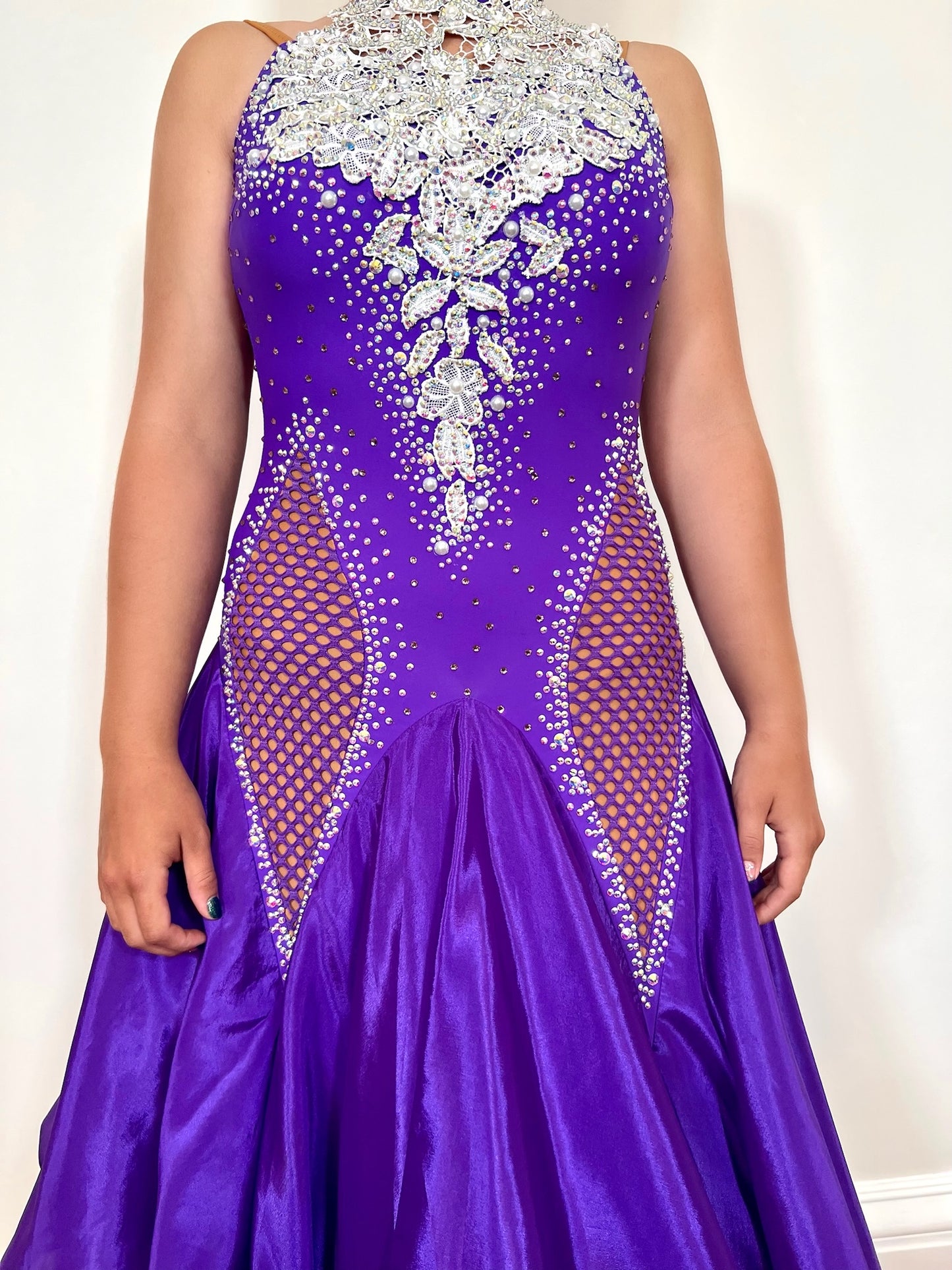 056 Purple Halter Neck Ballroom Dress. White lace detail to front and back bodice. Purple fishnet panel to the front. Decorated in purple & AB stones. Underskirts in White with exposed satin skirts to one side