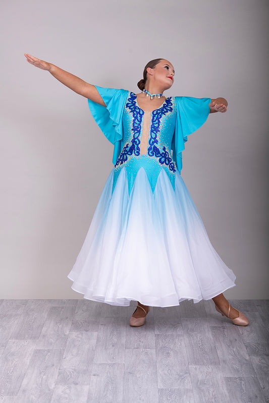 034 Turquoise & White ombré Ballroom Dress. Feature floaty sleeves & flesh panel detail to the chest. Decorated with royal blue motifs. Stoned in sapphire, light sapphire & AB