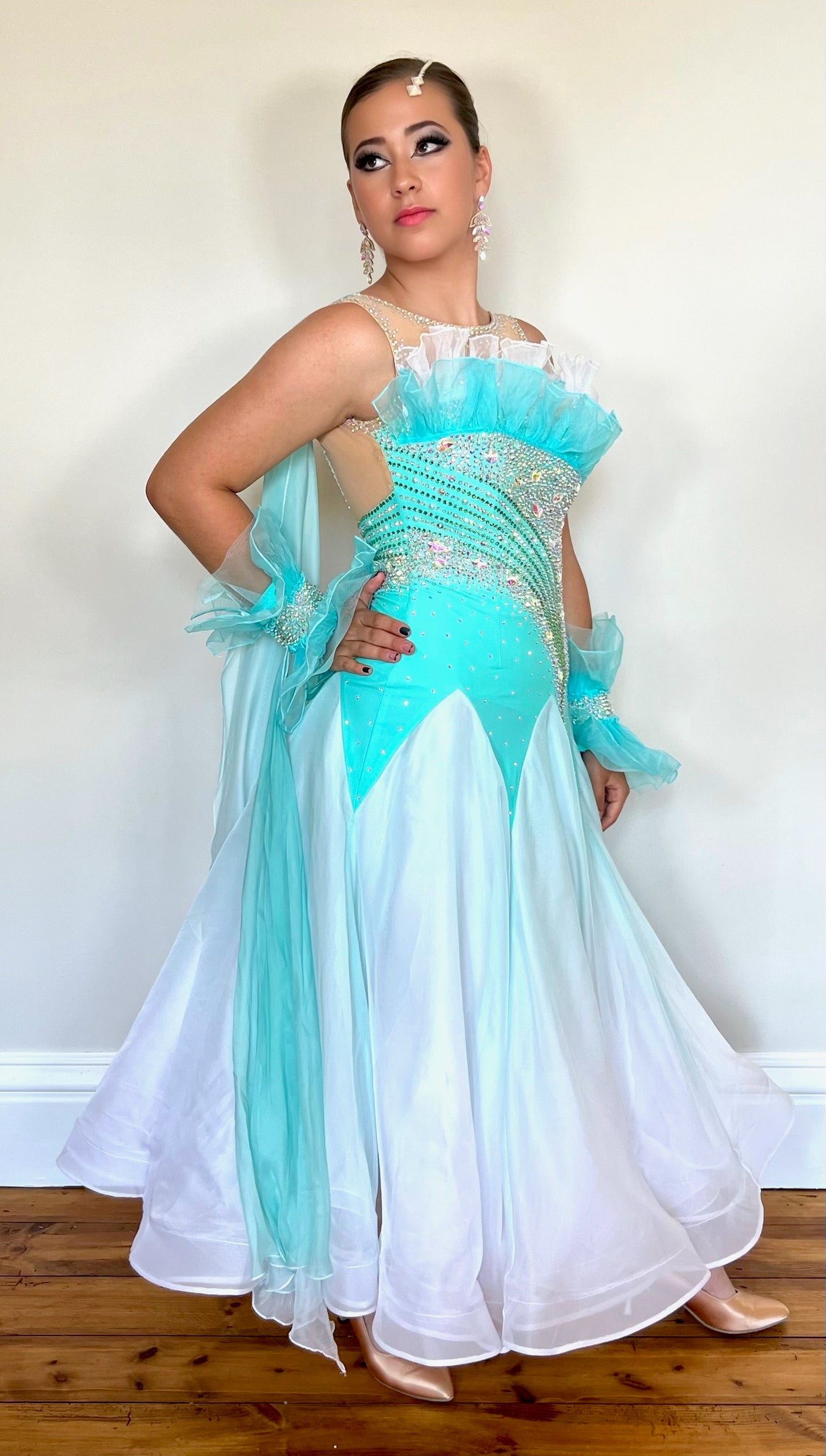043 Bright Aqua & Green & White Ombré Ballroom Dress. Organza frill detailing to the upper chest. Decorative organza cuffs with ombré floats attached to the back on one side. Separate hanging float to the opposite side. Decorated in AB stones.